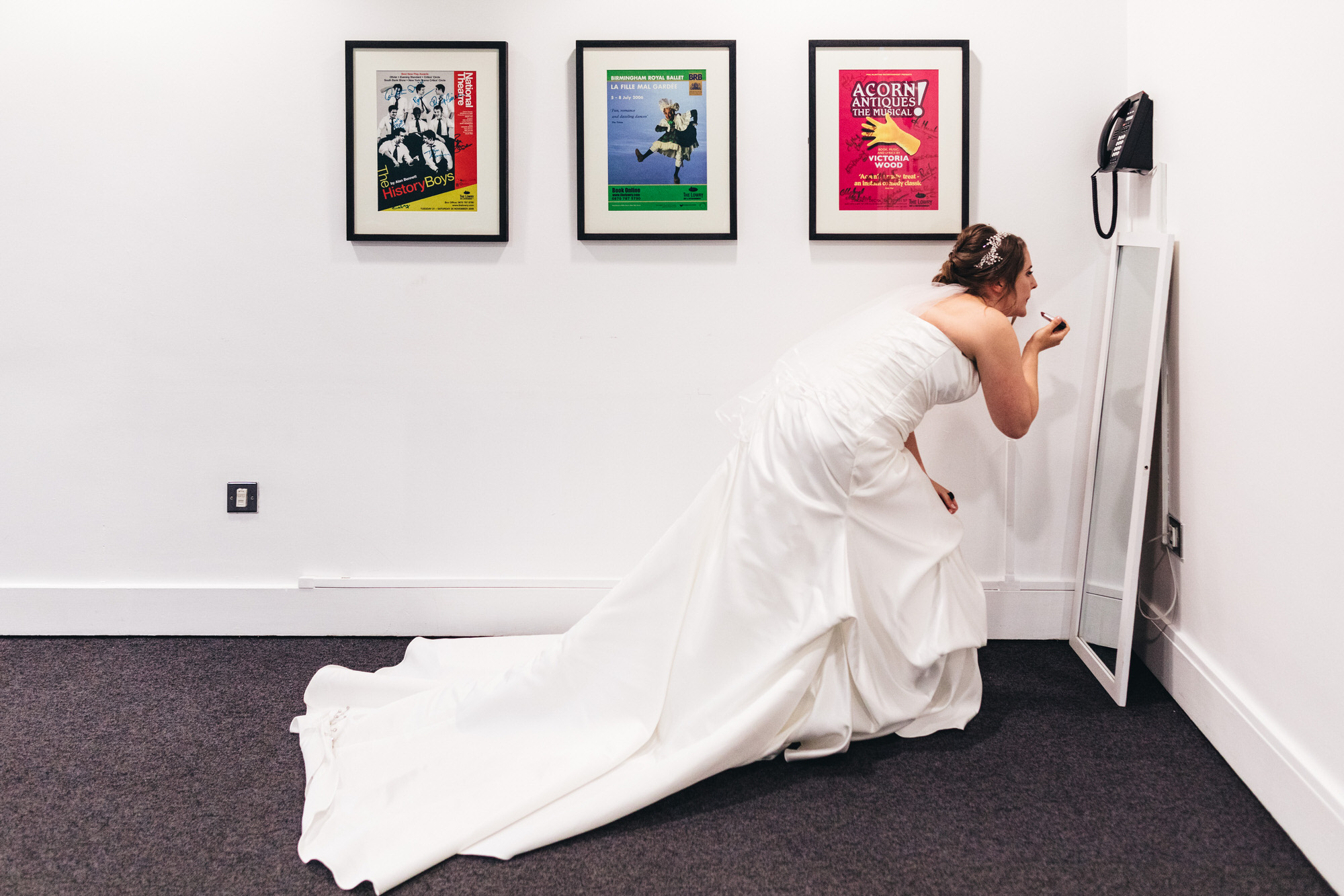 bride touches up lipstick in mirror