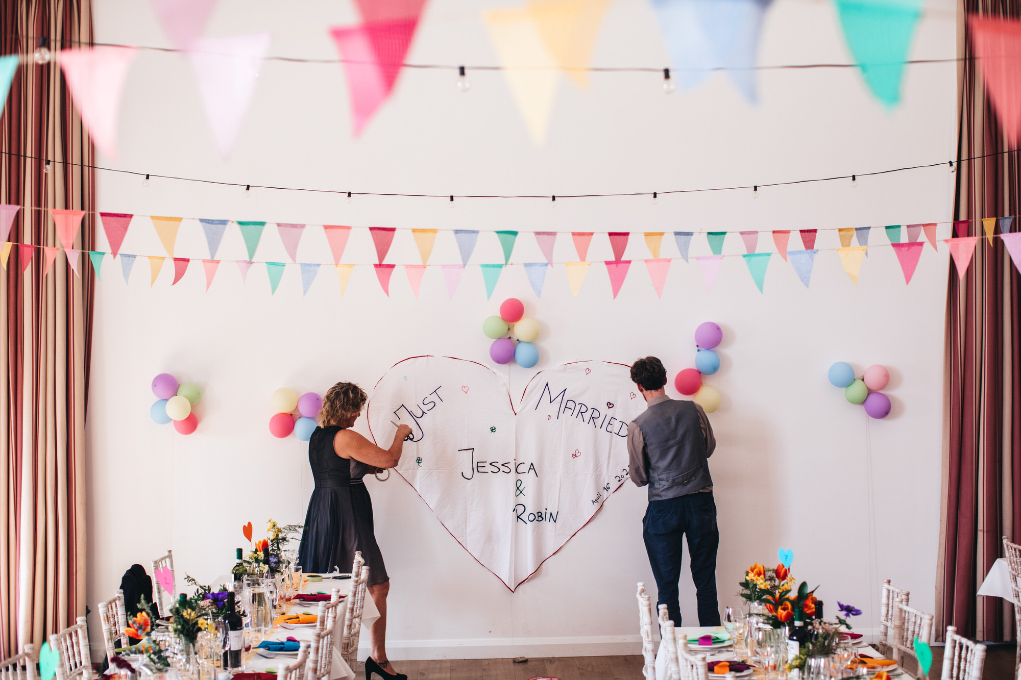 diy village hall wedding two people attach just married sign to wall