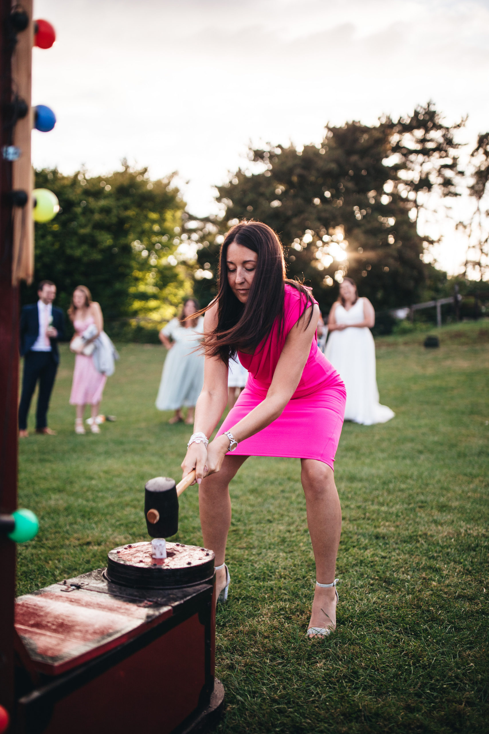 women plays strongman game at wedding in pink dress
