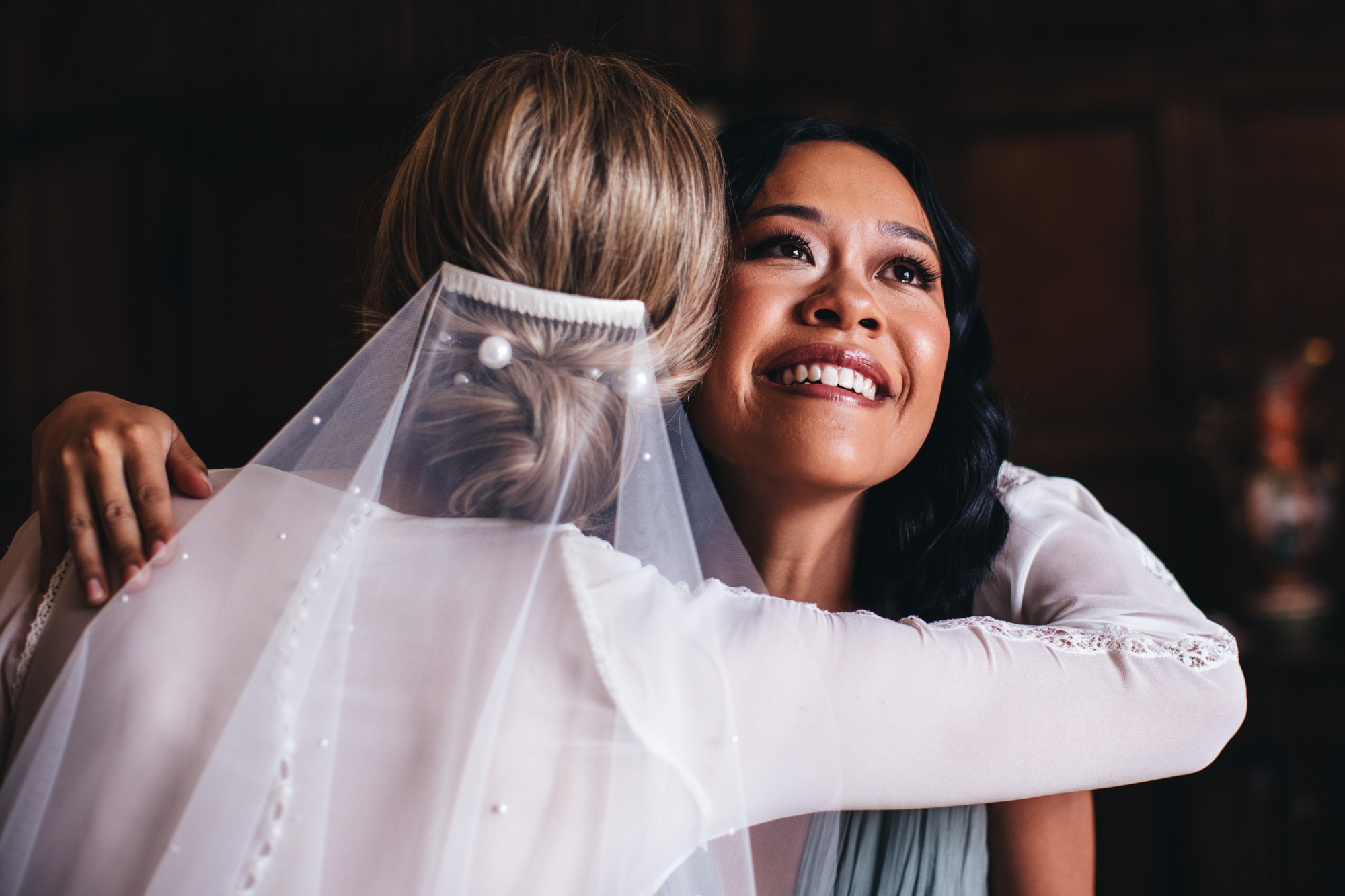 teary friend hugging bride and holding her veil