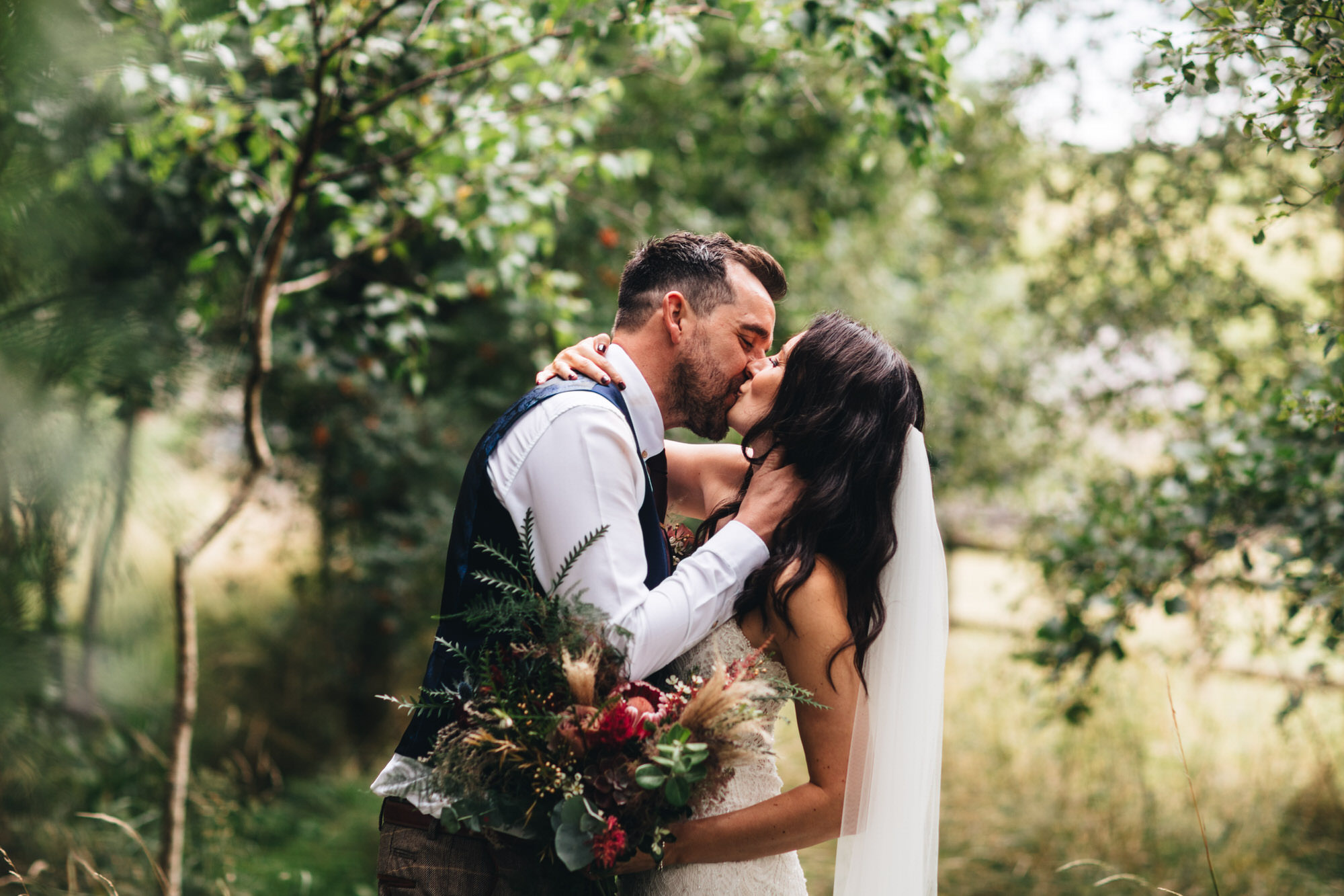 Newly weds kiss under trees in peak district
