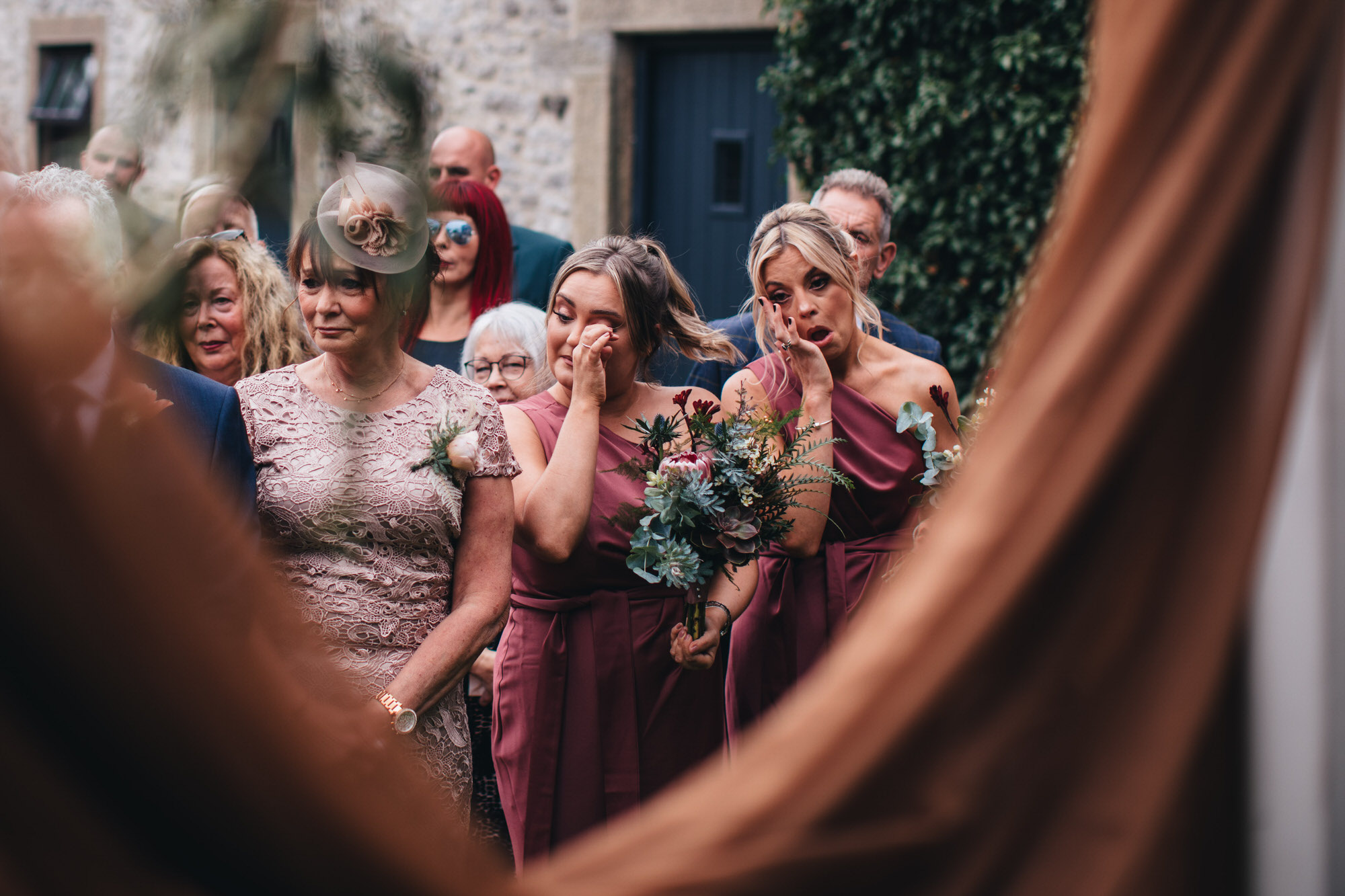 bridesmaids wiping tears away during wedding ceremony