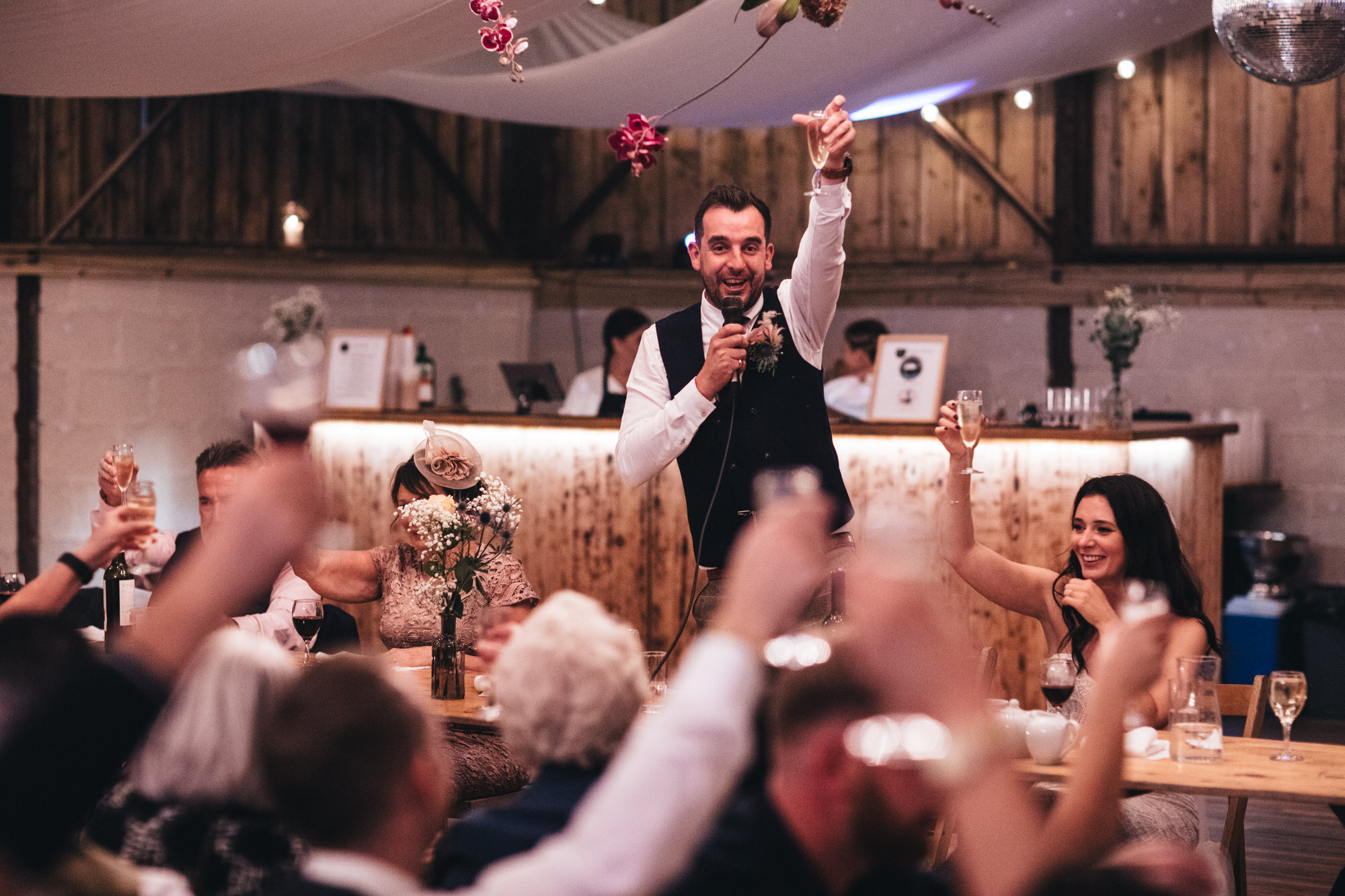 groom raises glass to toast with guests