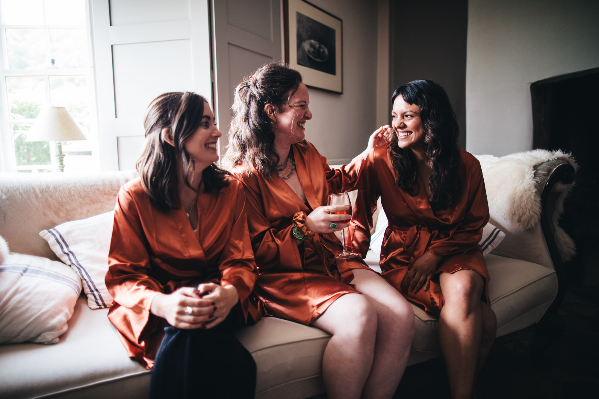 bride laughing with bridesmaids in matching dressing gowns kimonos