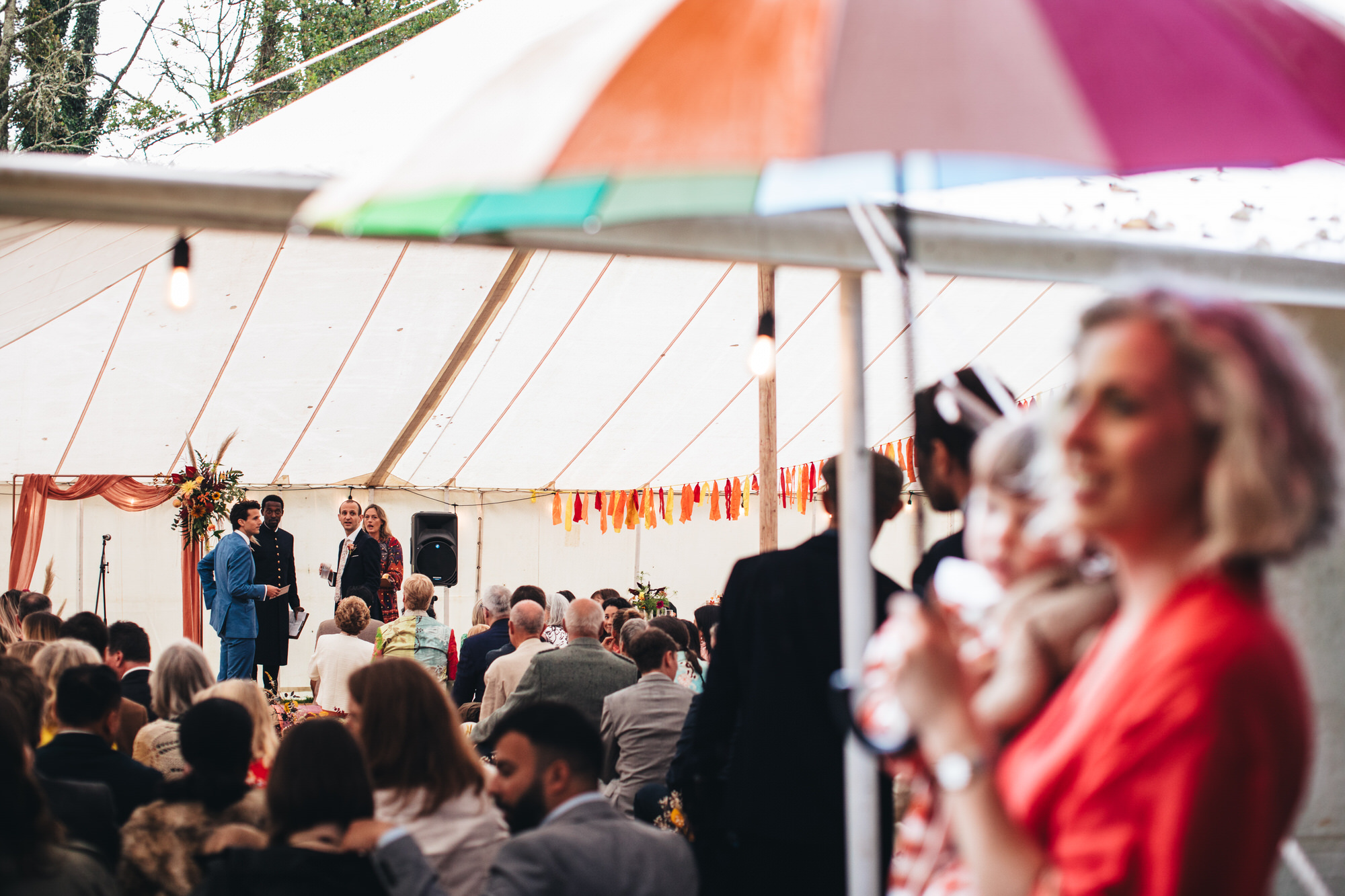 groom waiting by stage inside marquee tent