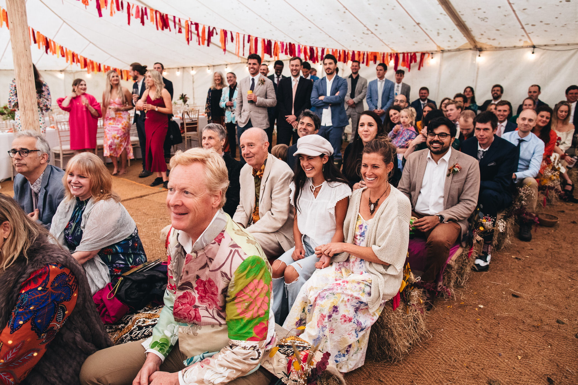 laughing wedding guests sitting on hay bales