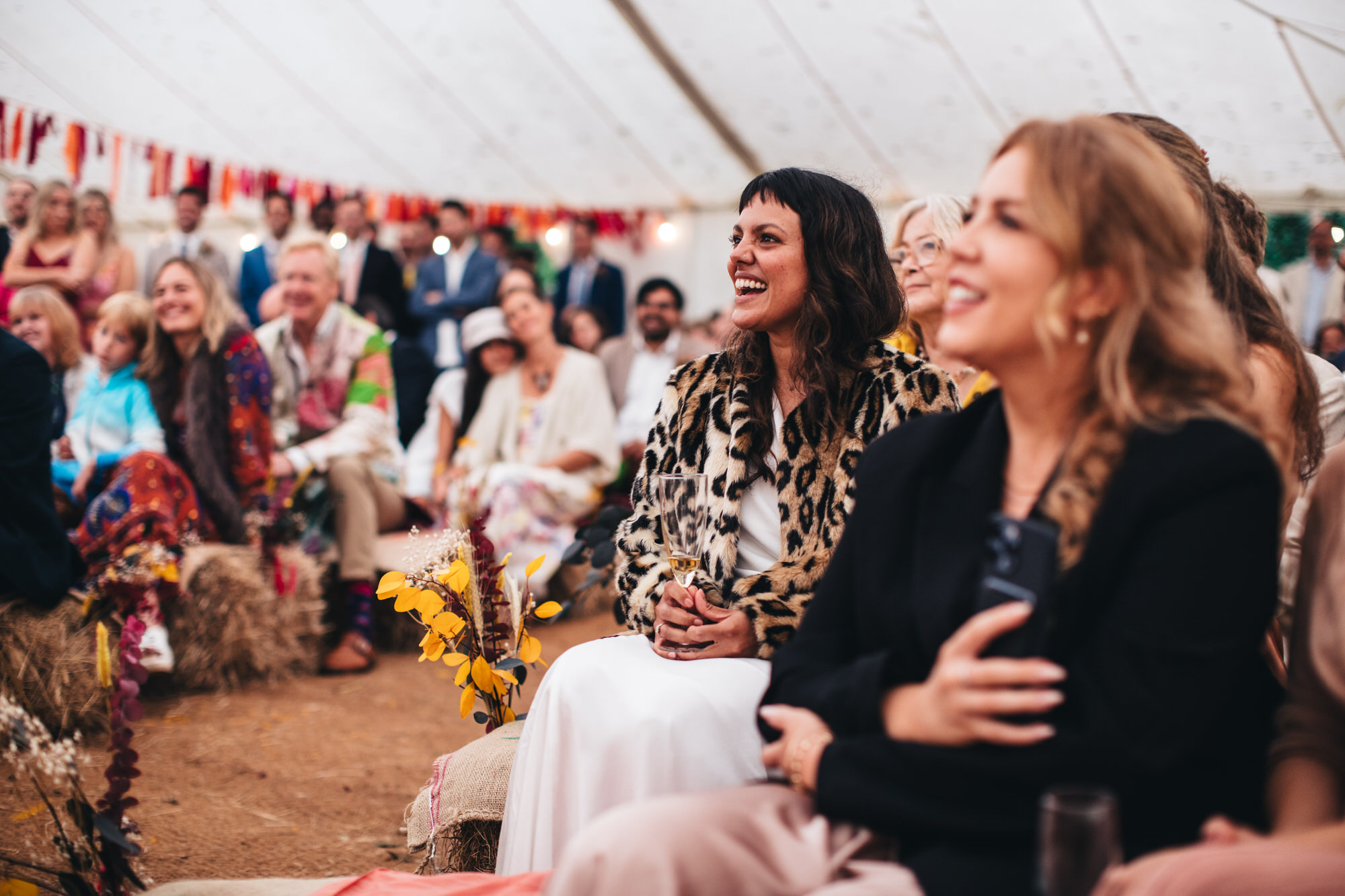 bride laughing with guests sitting on hay bales