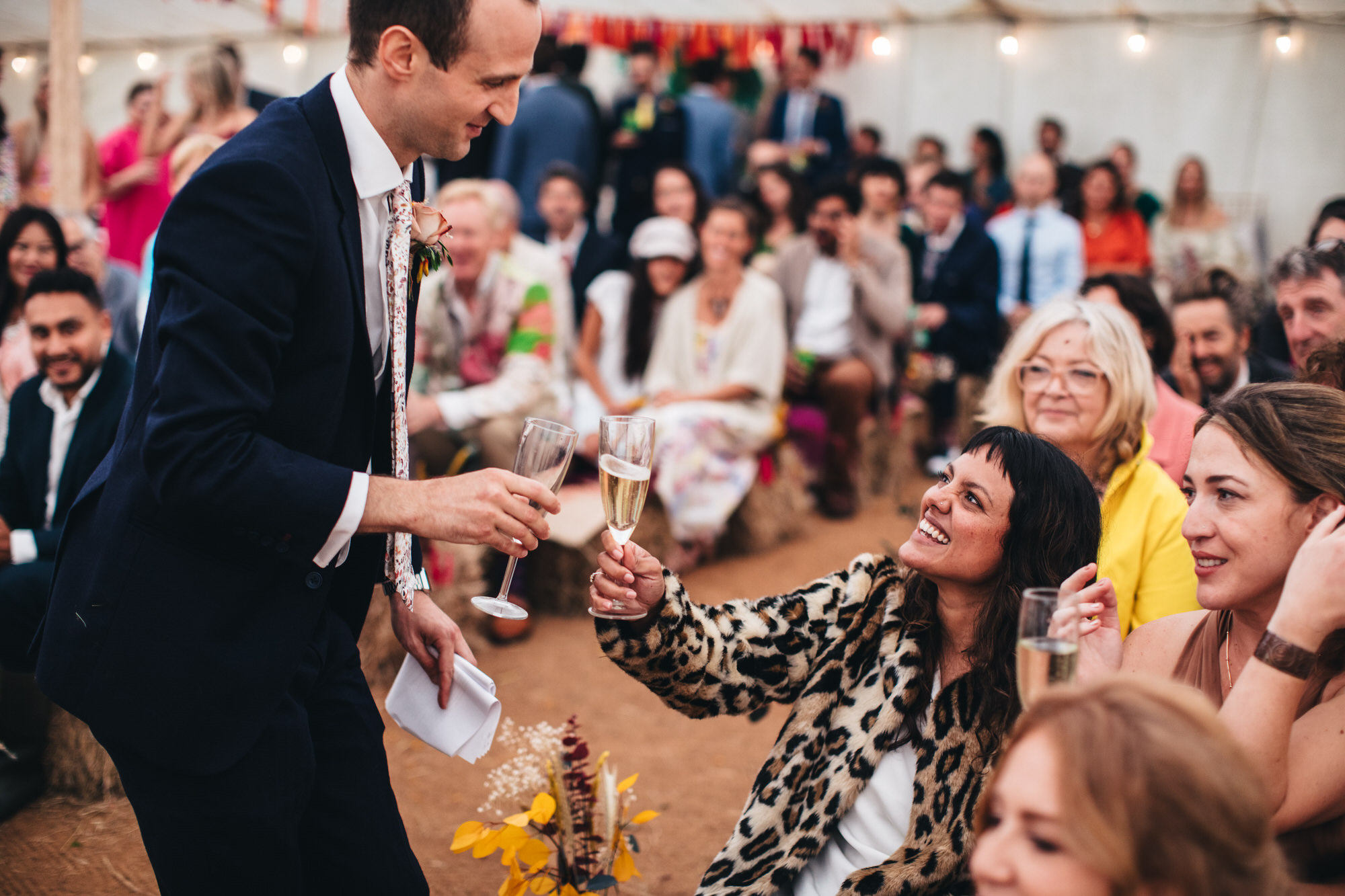 groom cheersing bride with champagne in front of guests