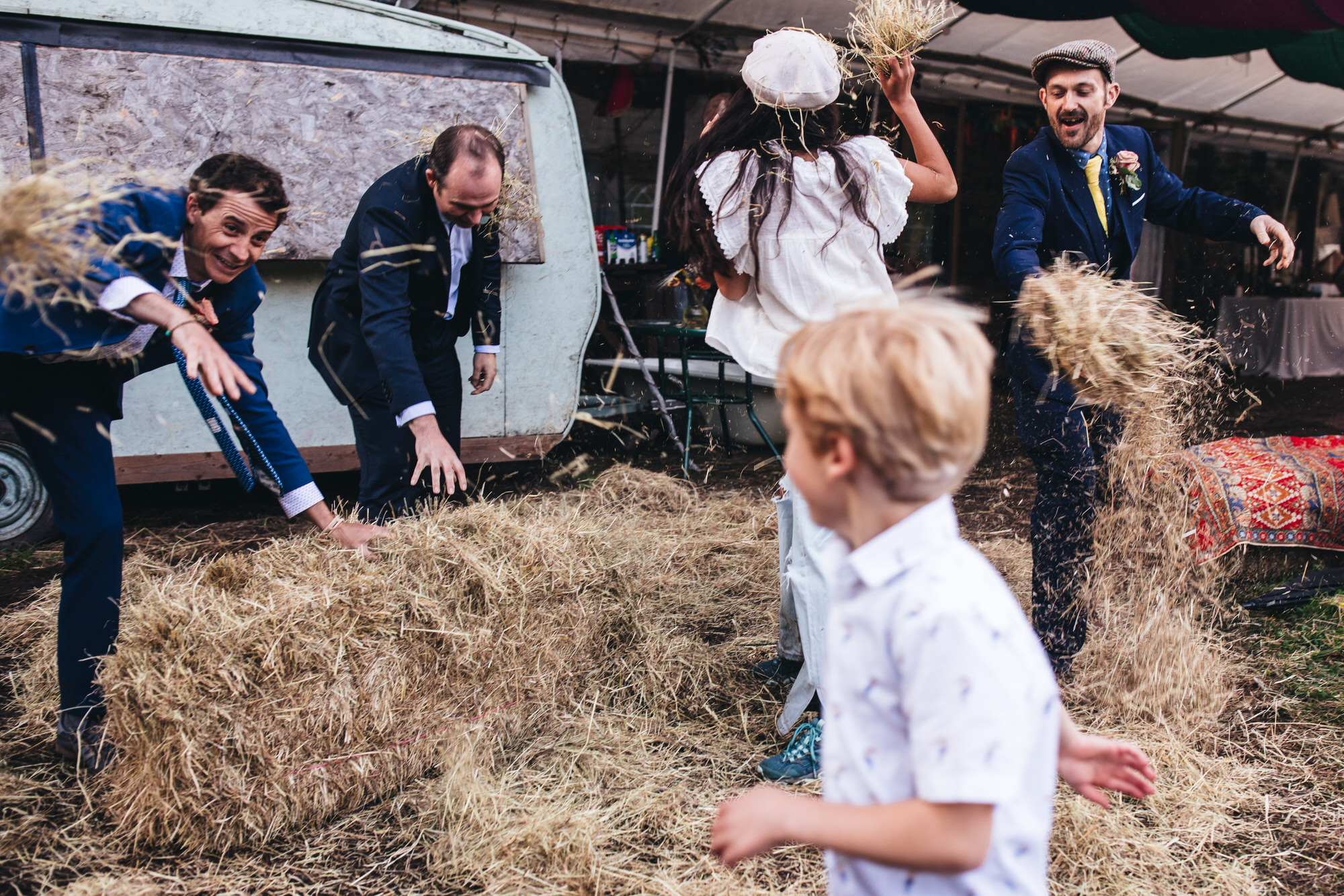 groomsmen in suits throwing hay at child