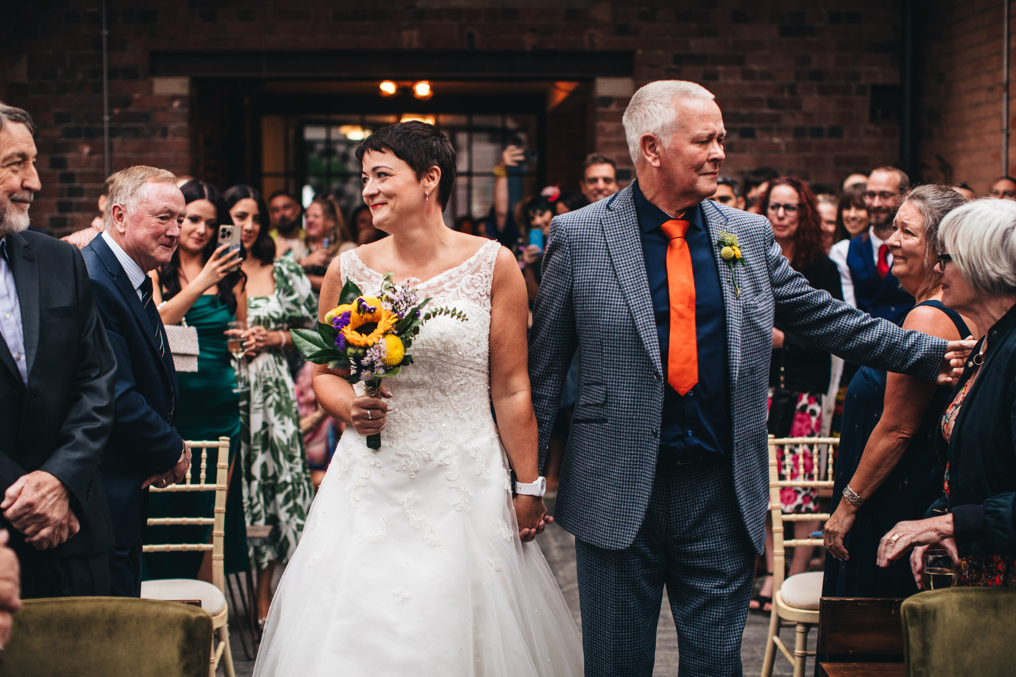 emotional bride walking down aisle with father and sunflower bouquet
