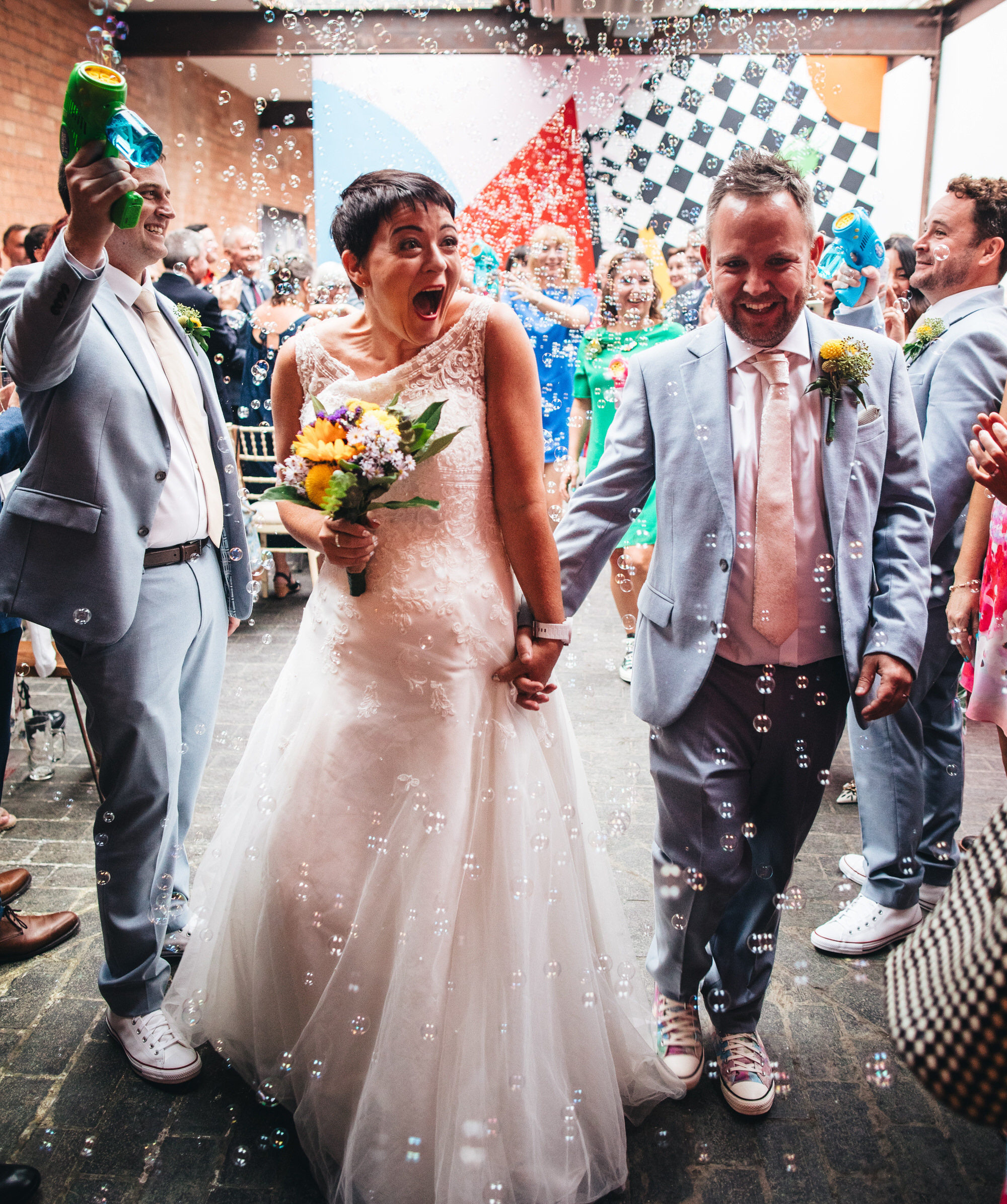 bride and groom laughing surrounded by bubbles confetti shot