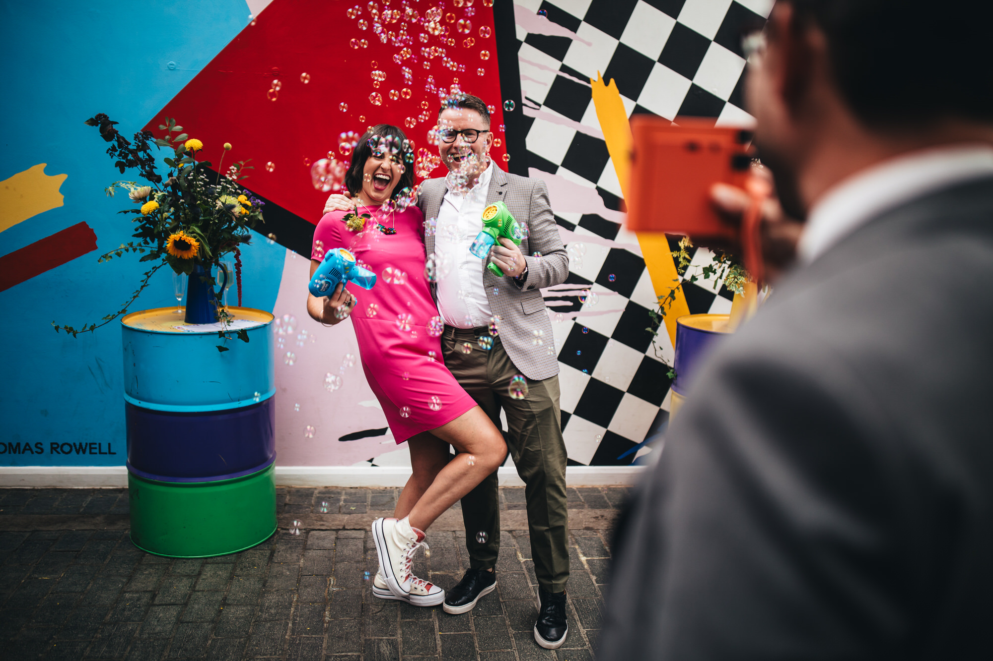 bridesmaid poses for photo with man in suit surrounded by bubbles