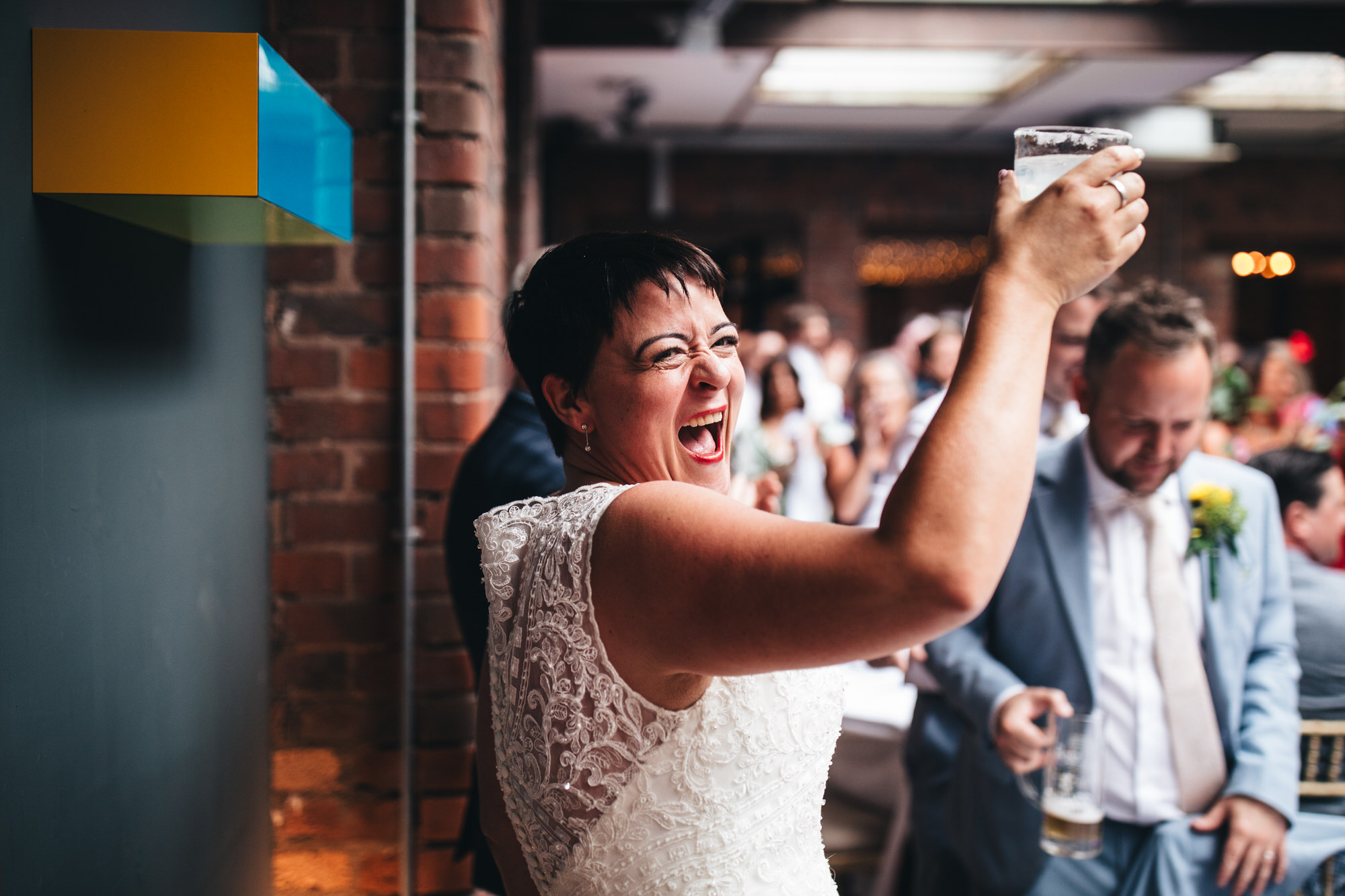 bride holds up cocktail, laughing