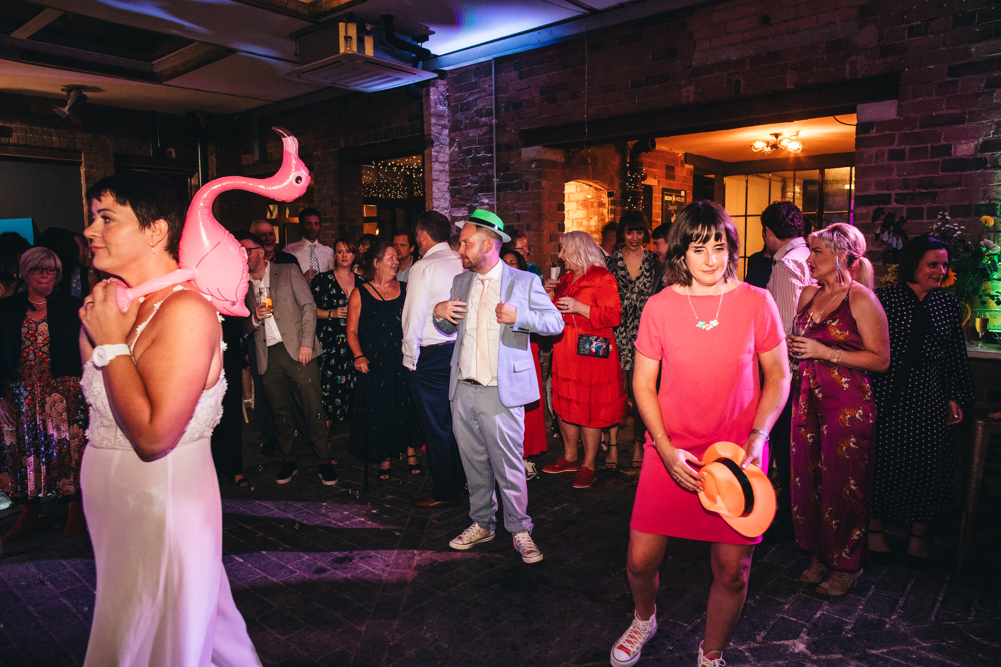bride with inflatable flamingo, guests on dancefloor