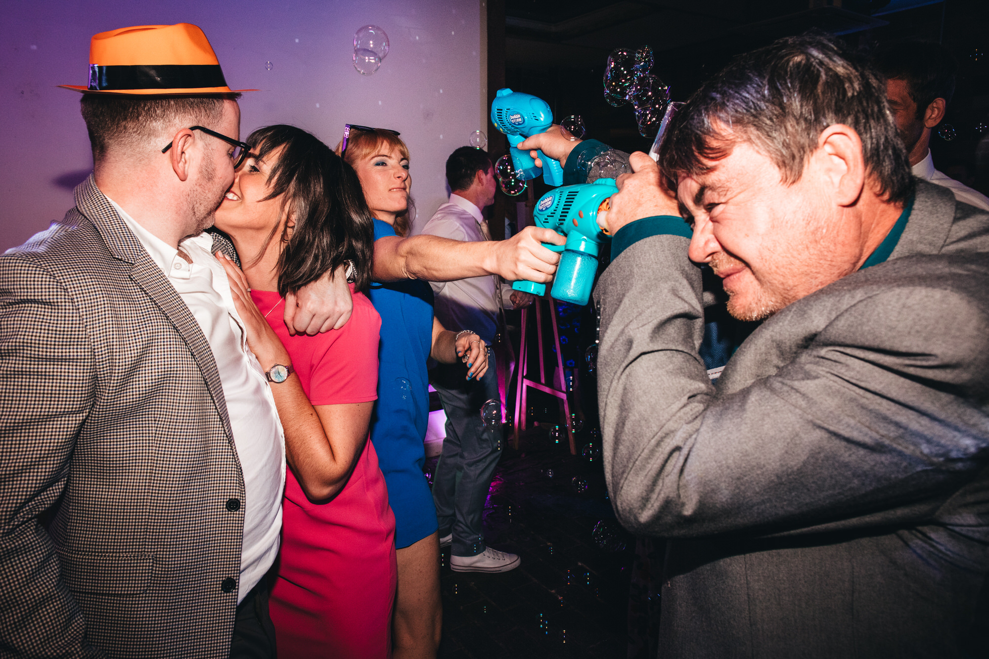 guests kissing on dancefloor, bubble gun fight