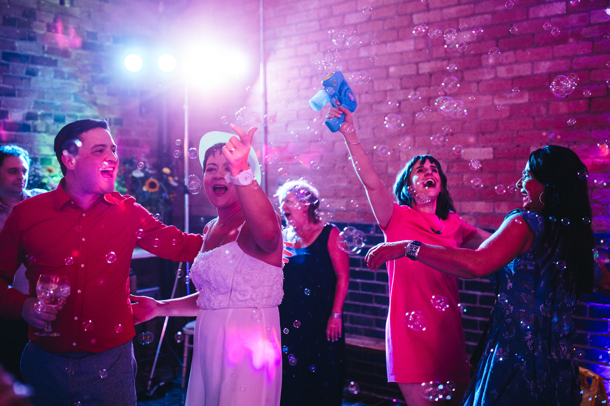 Bride and guests dancing on dancefloor and playing with bubble gun