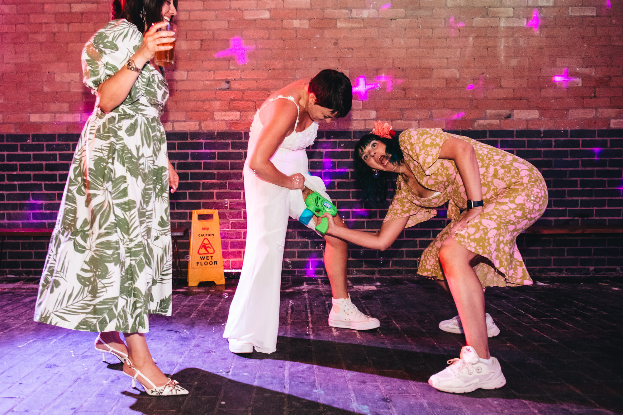 guest with bubble gun inserted in pant leg of bride's wedding jumpsuit