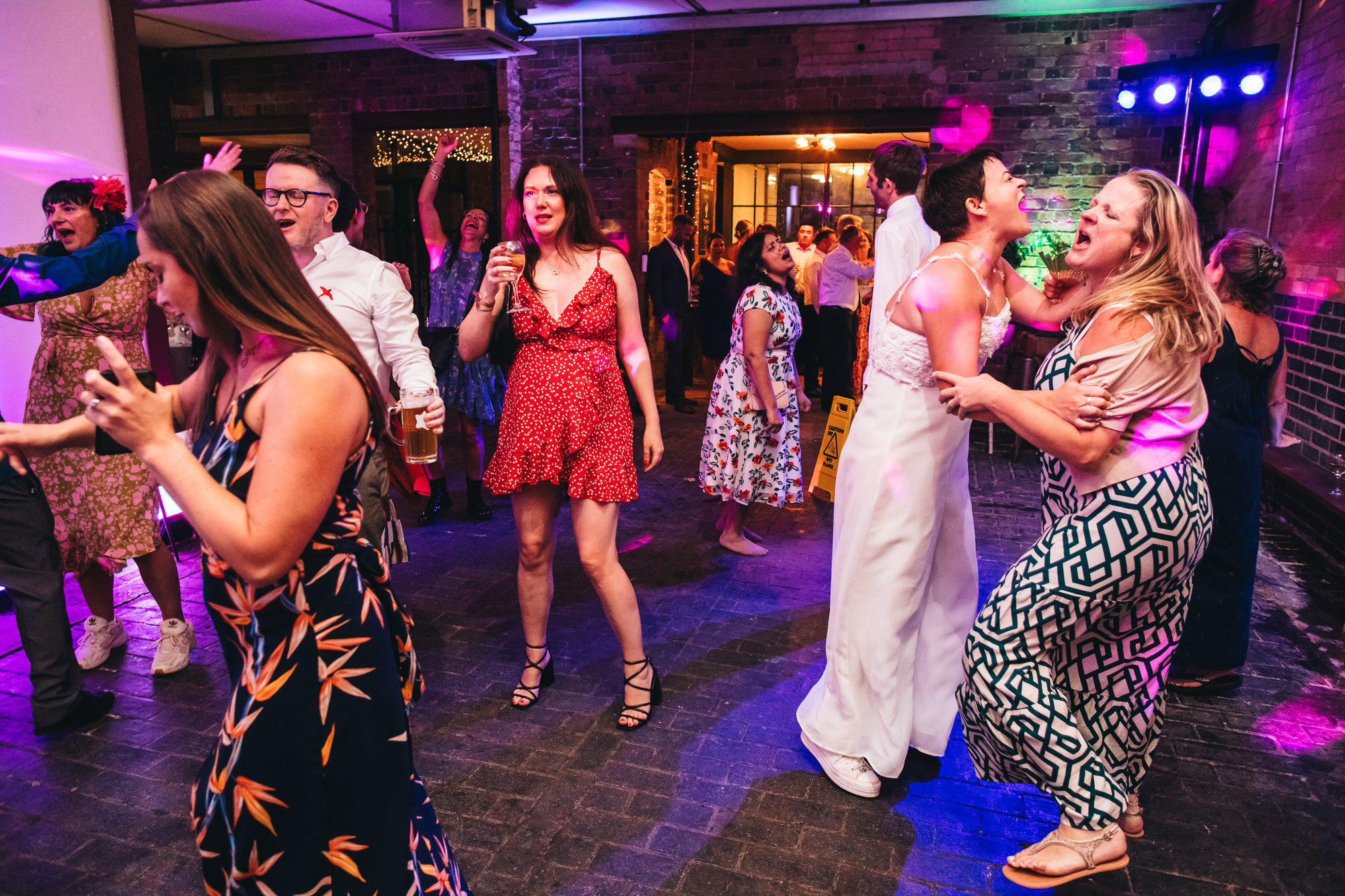 bride and wedding guests dancing energetically on dancefloor