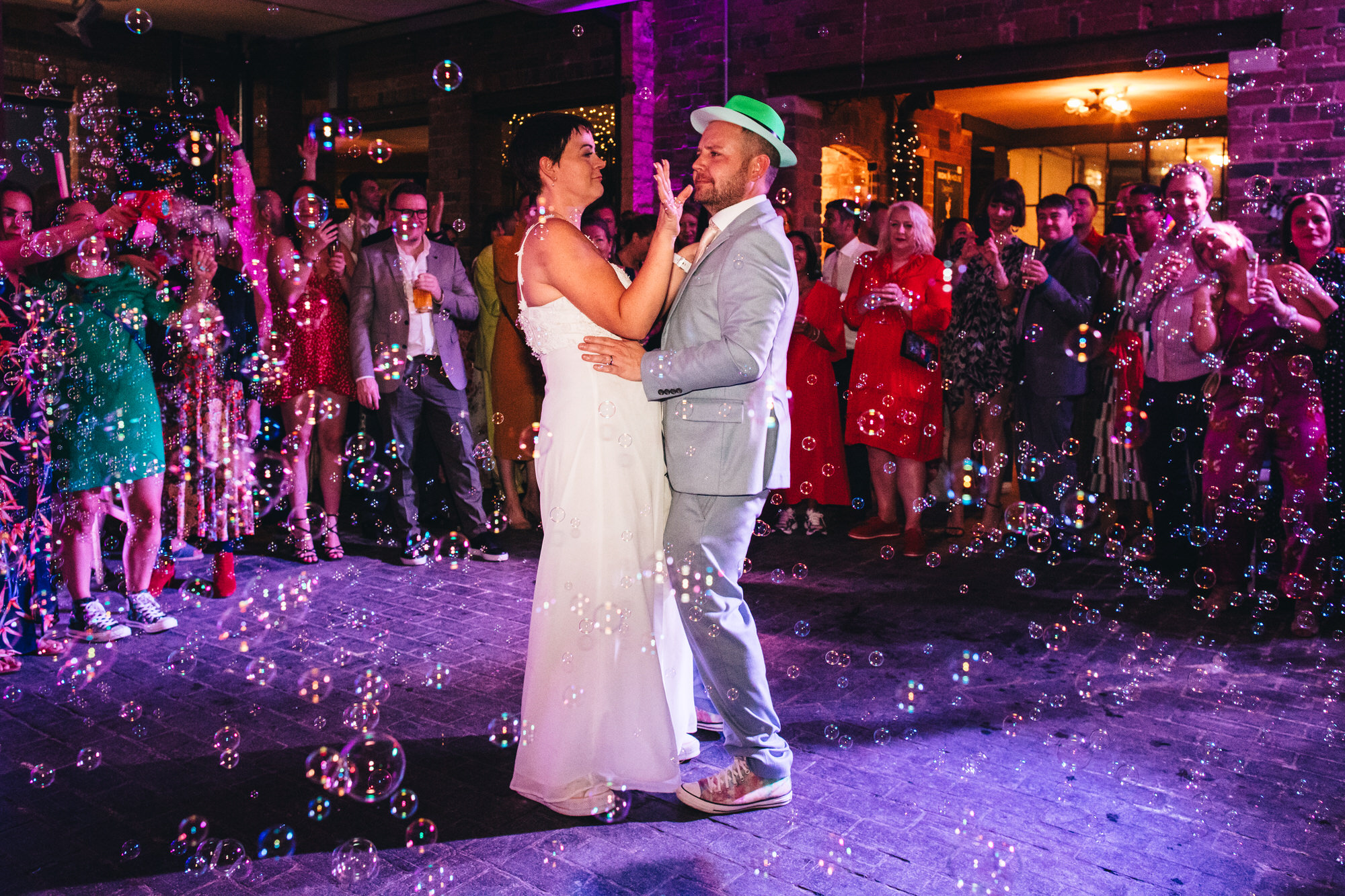 Iron house wedding first dance groom wears party bowlers hat the couple are surrounded by bubbles