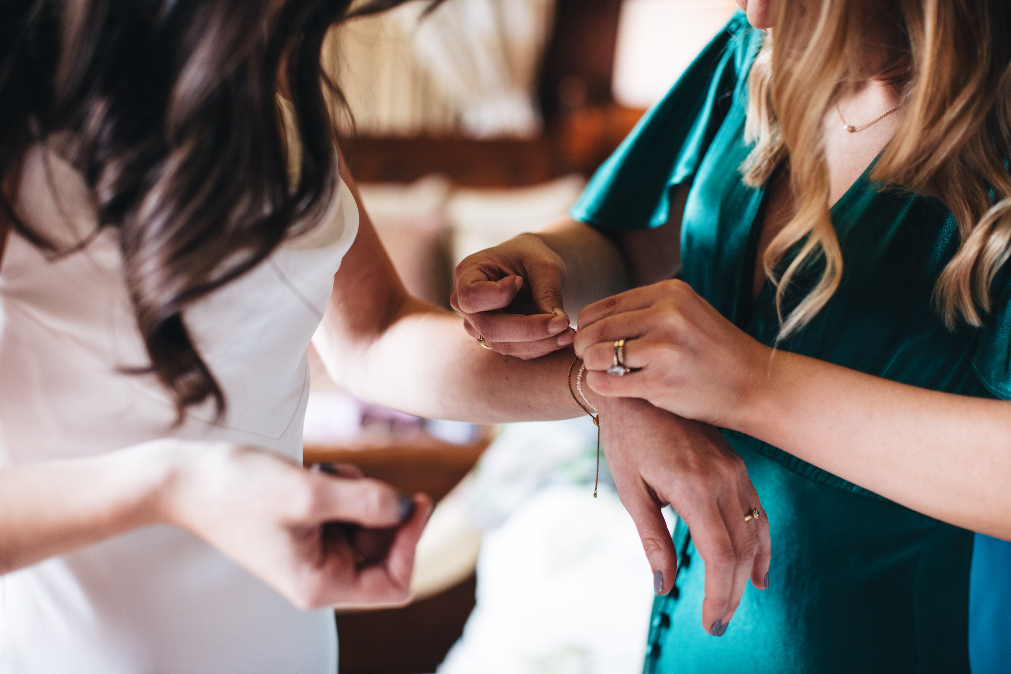bridesmaid, bridal prep, putting bracelet on bride's wrist