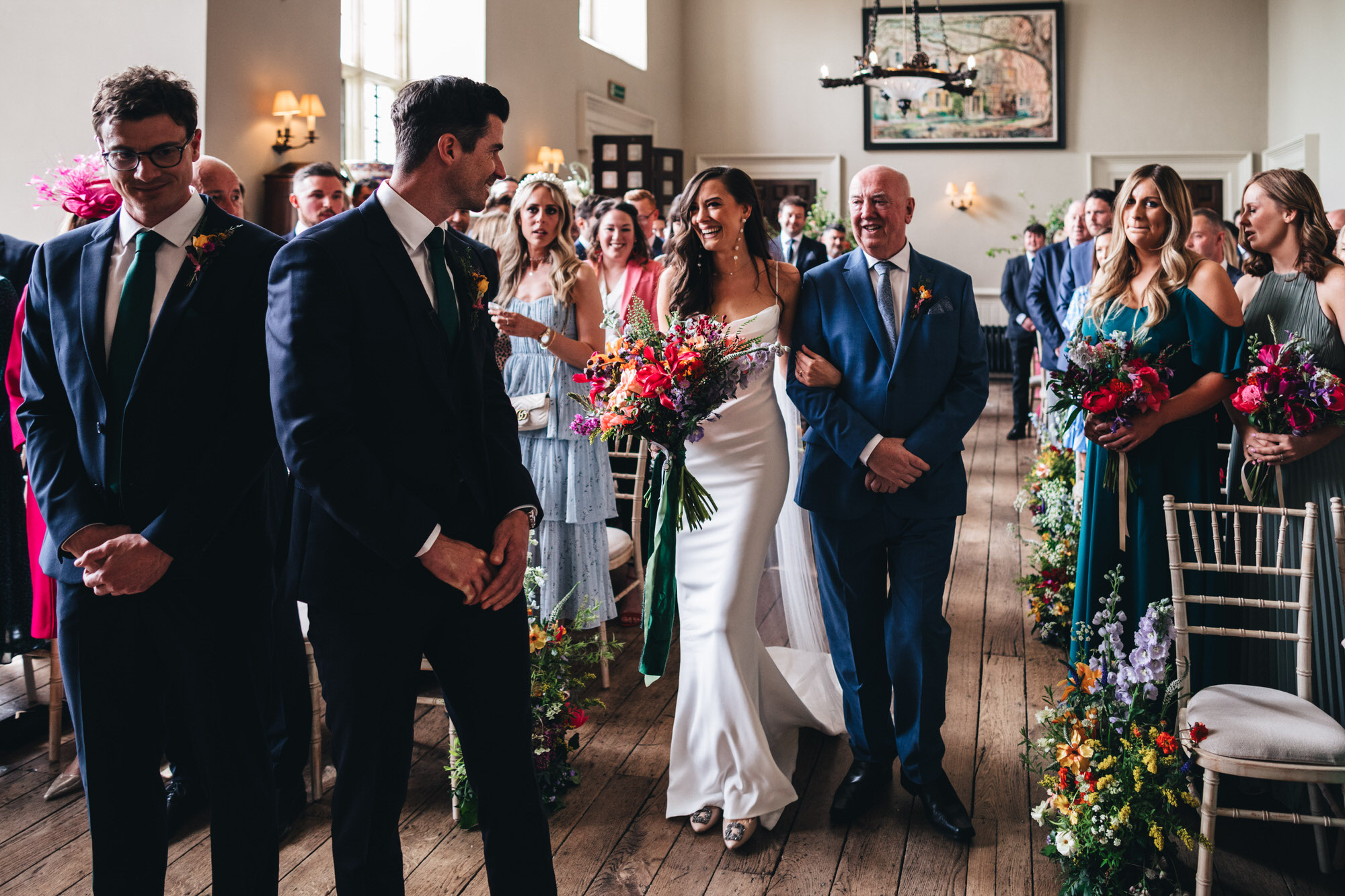 bride laughing with Wren and May bouquet, walking with father down aisle at Elmore Court Hall smiling at groom