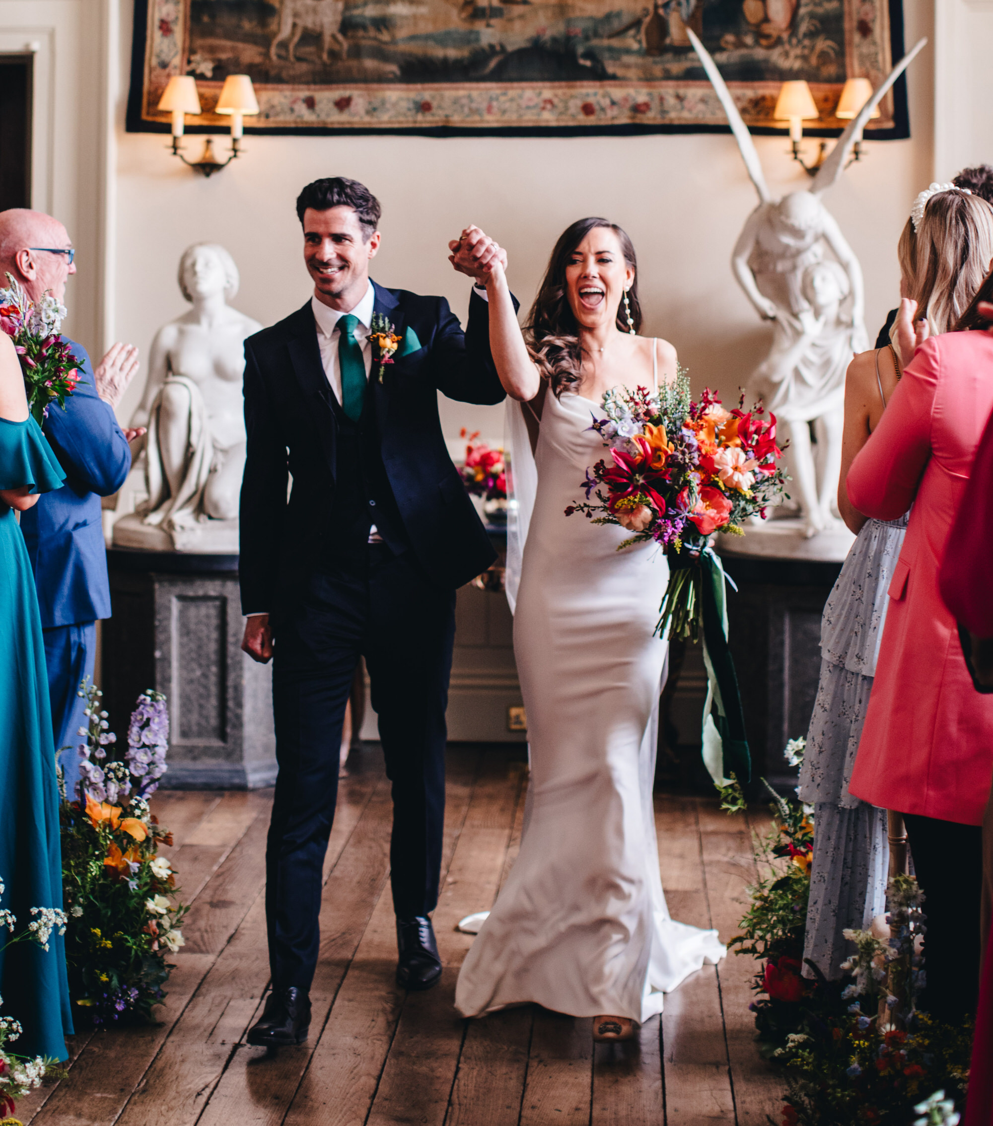 bride and groom holding hands cheering after wedding ceremony with Wren and May bouquet flowers