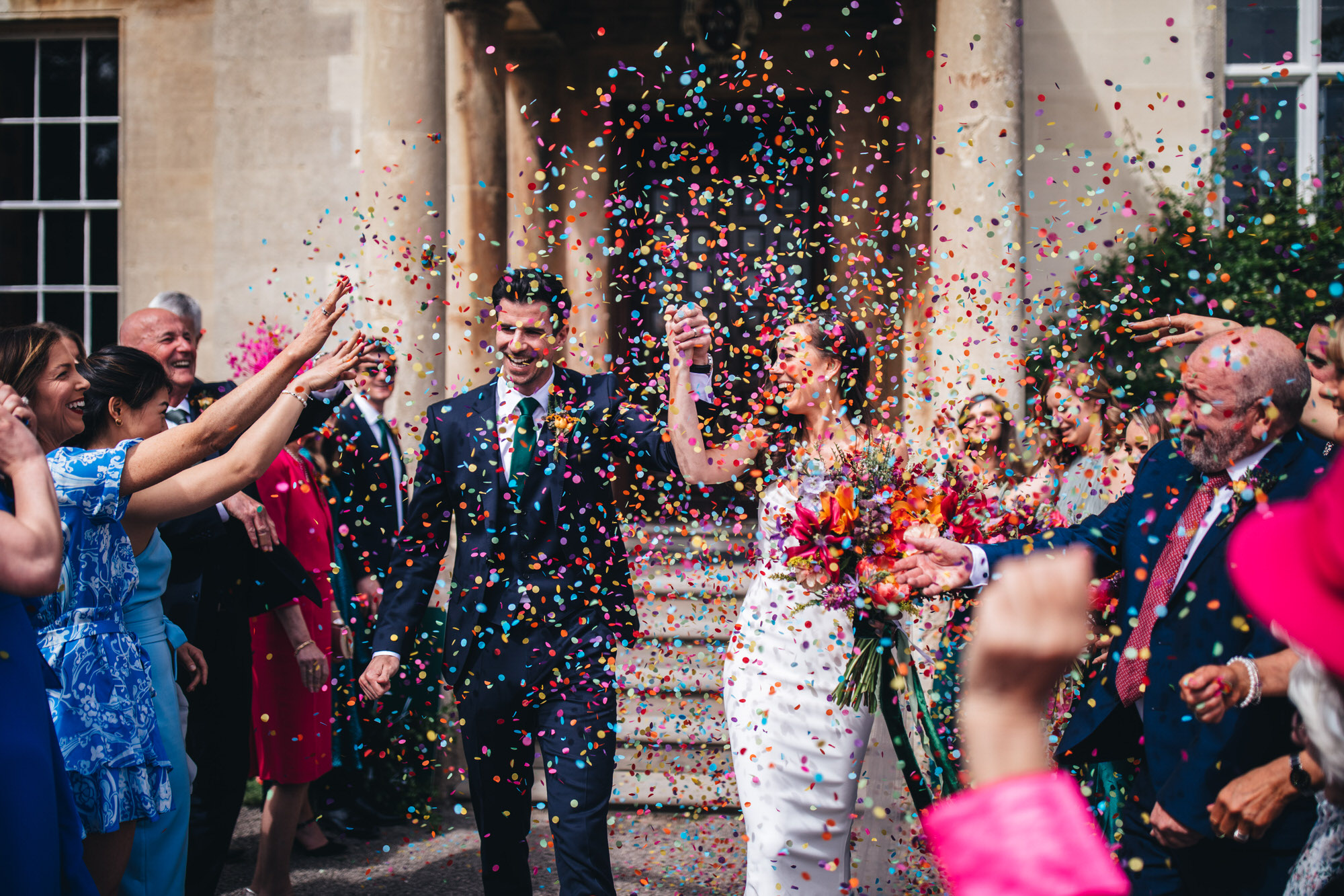 bride and groom as wedding guests throw confetti outside Elmore Hall, confetti shot, Elmore Court wedding photography