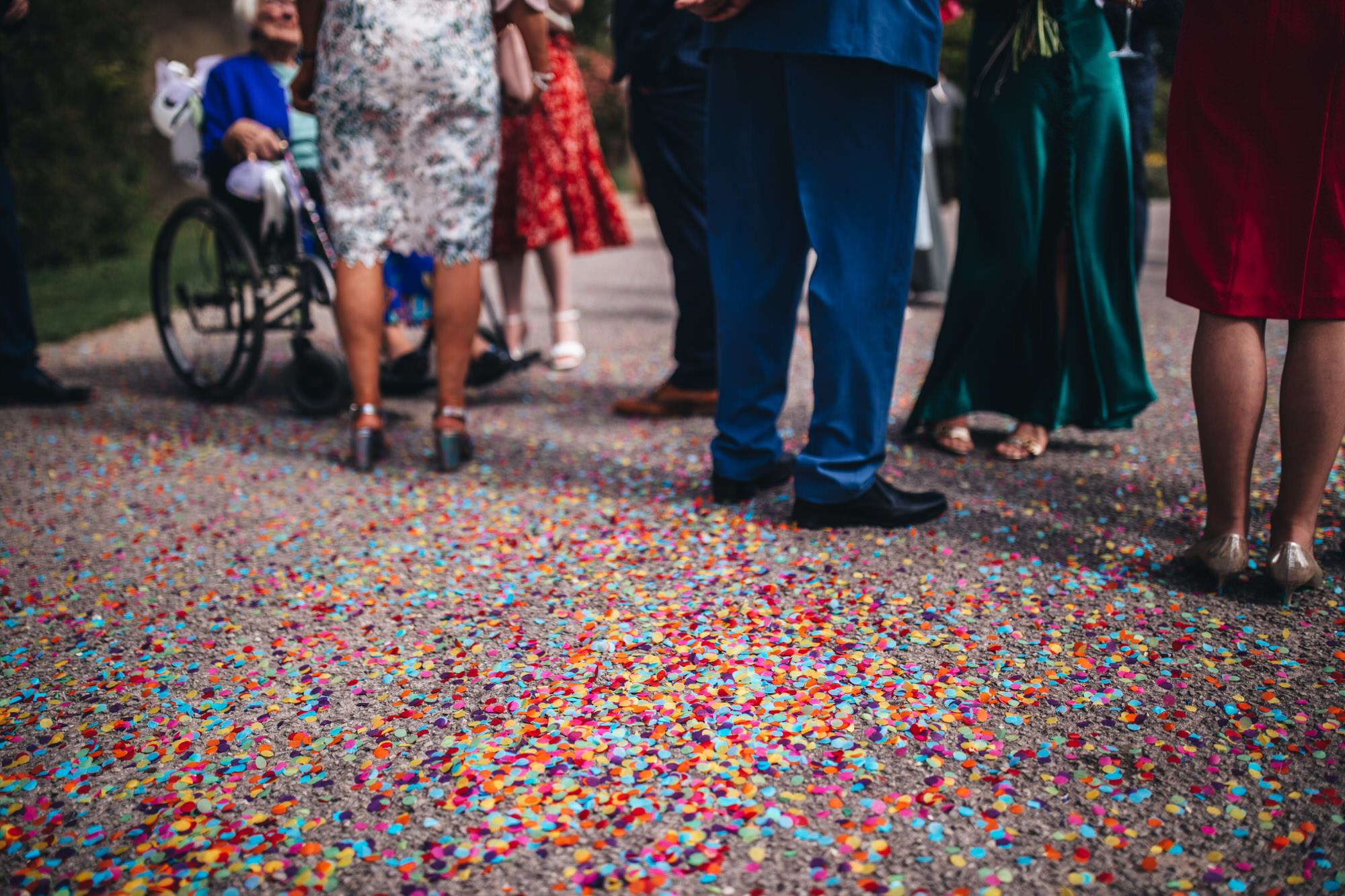 colourful paper confetti covering ground around wedding guests