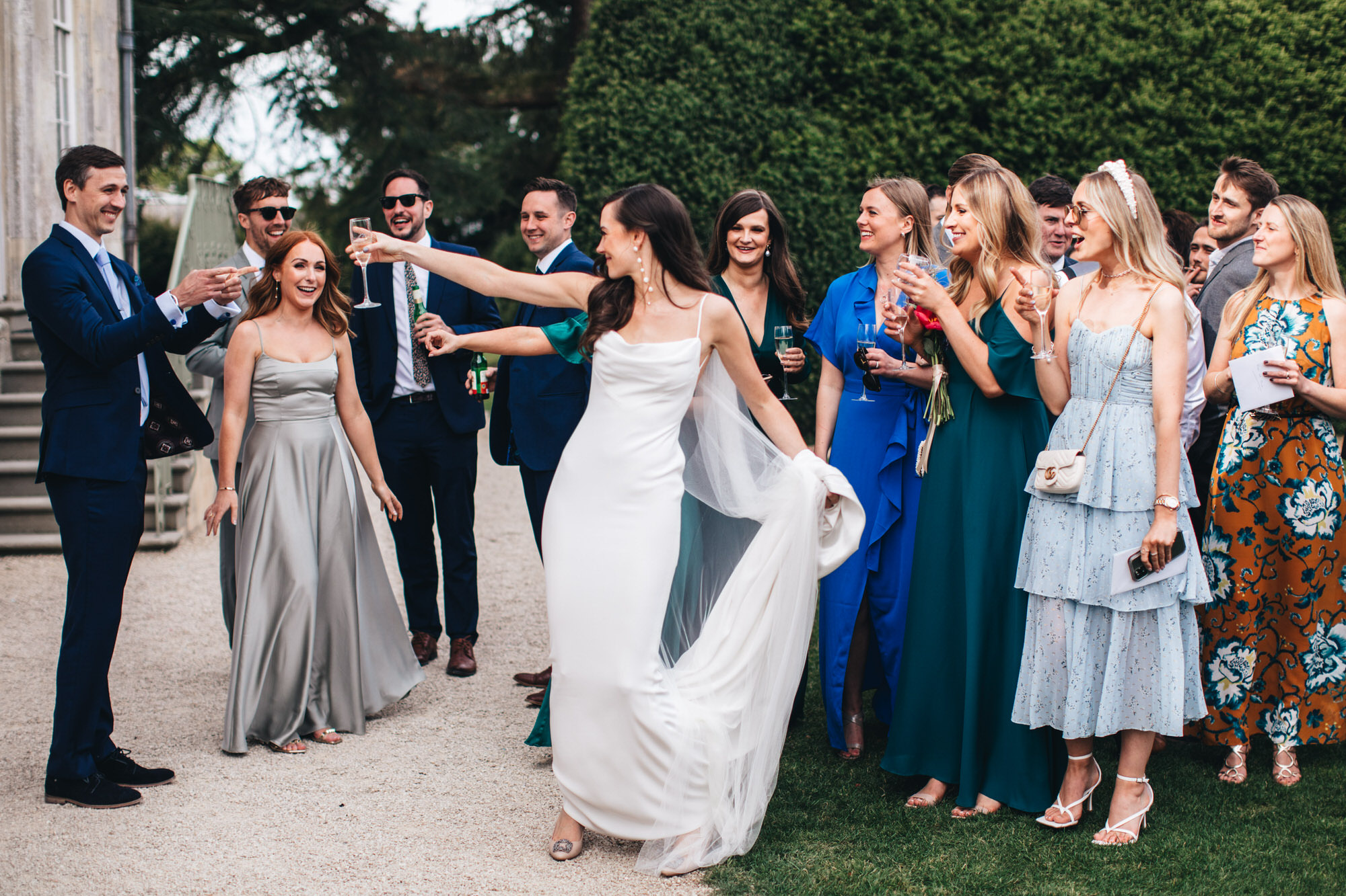 bride toasts wedding guests with glass of champagne, wearing Kyha wedding dress