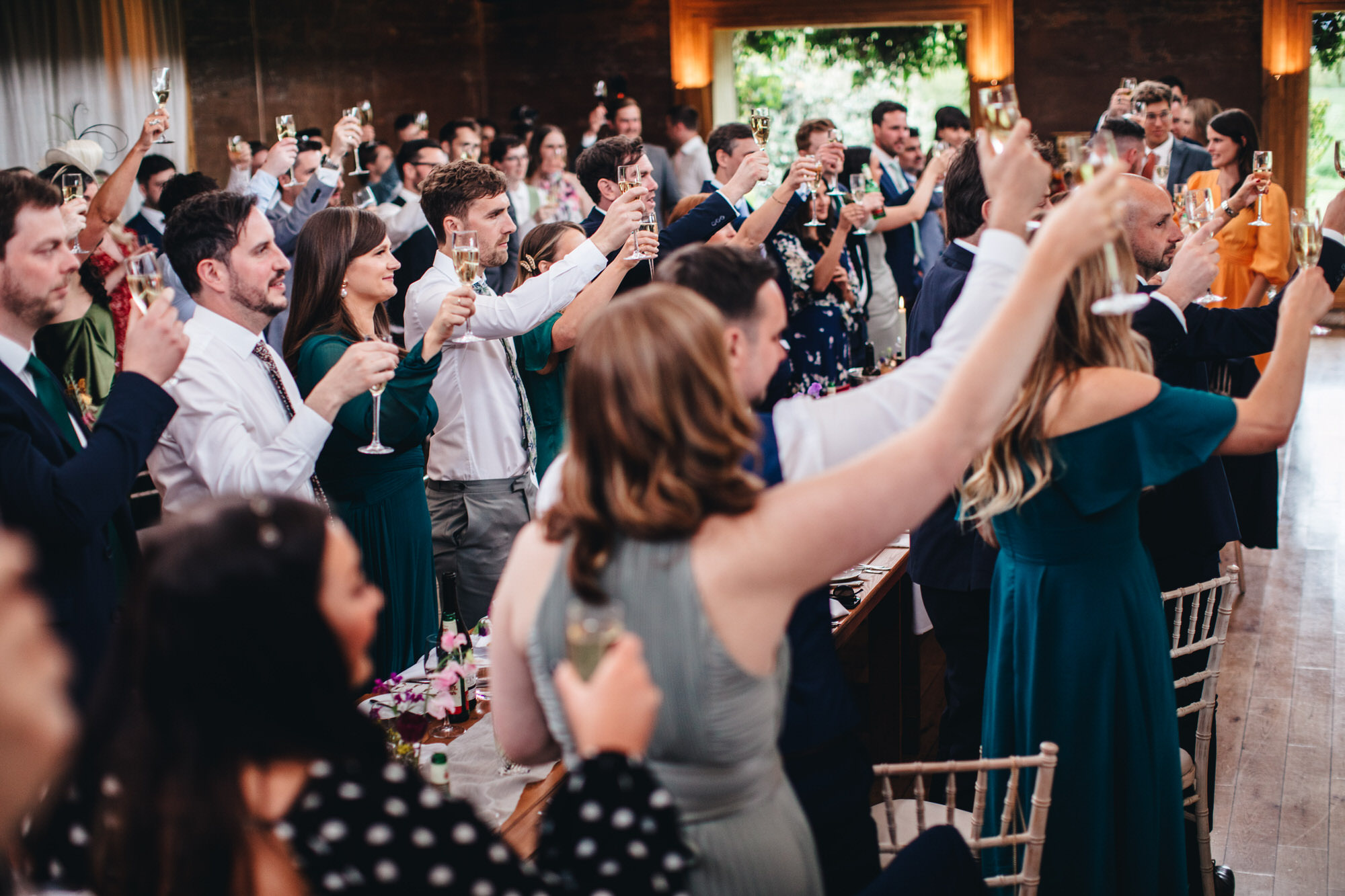 guests make wedding toast after speeches, raising glasses of champagne