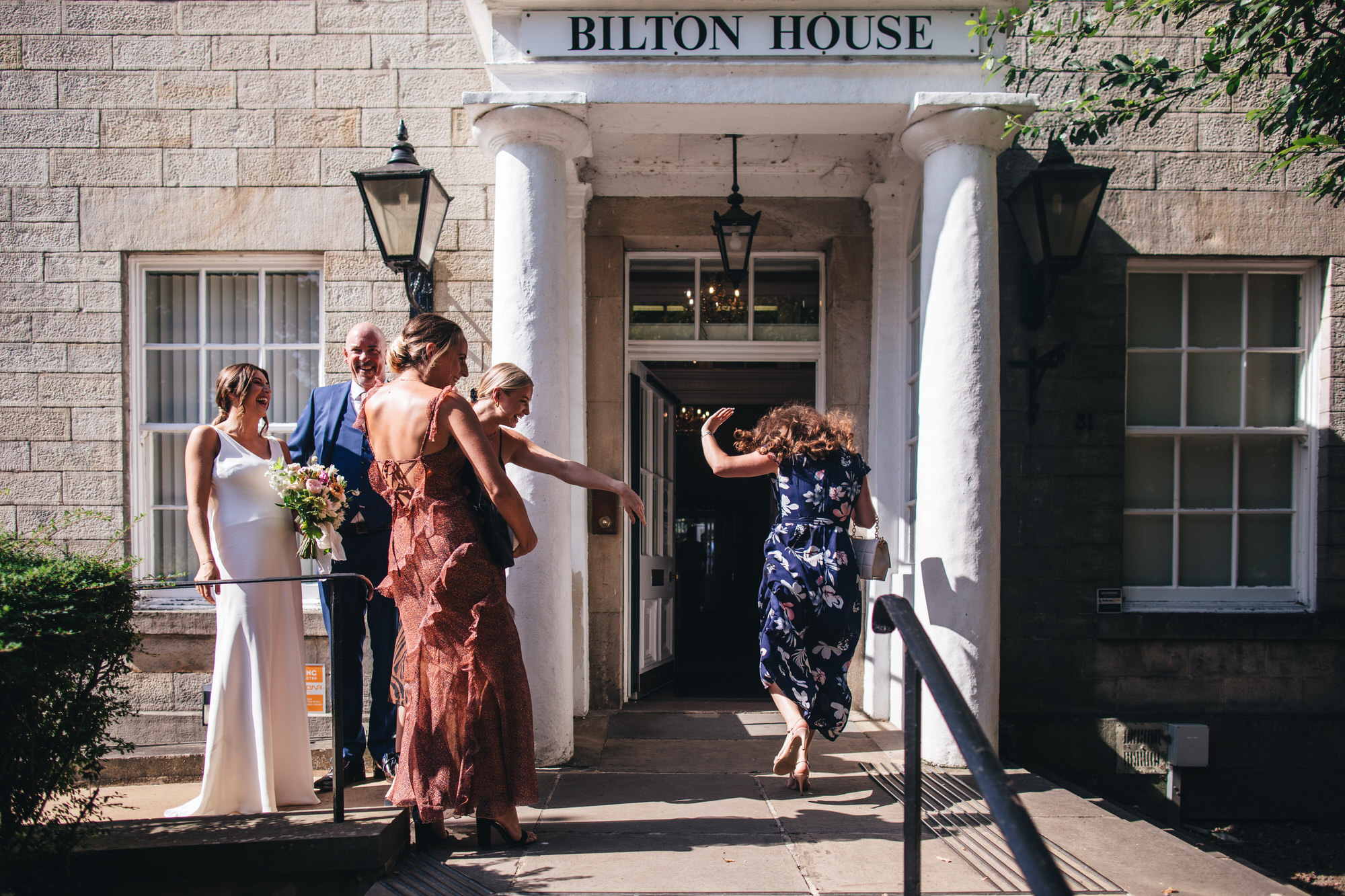 bride and bridal party laughing outside Bilton House