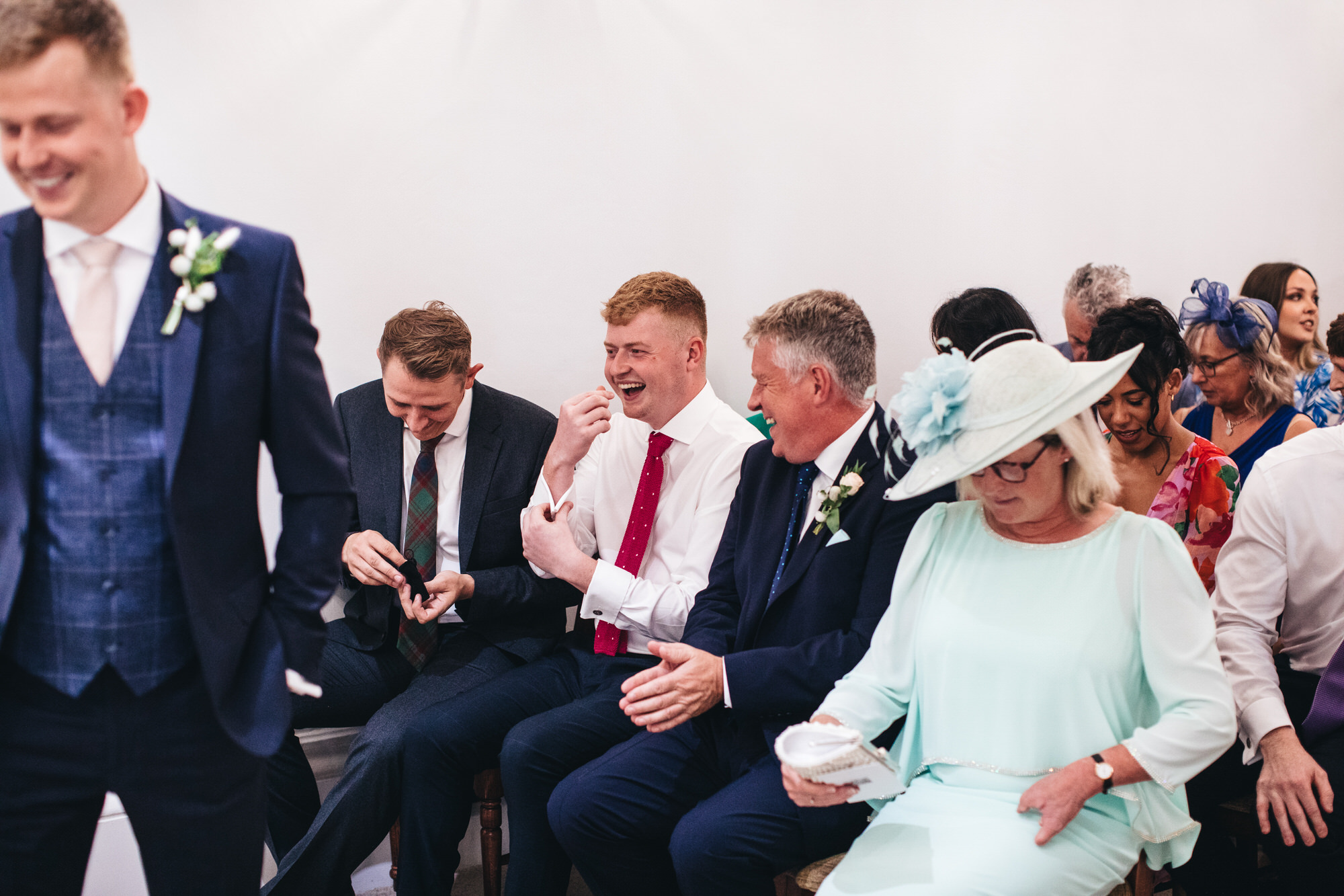 guests, groomsmen sitting laughing in ceremony