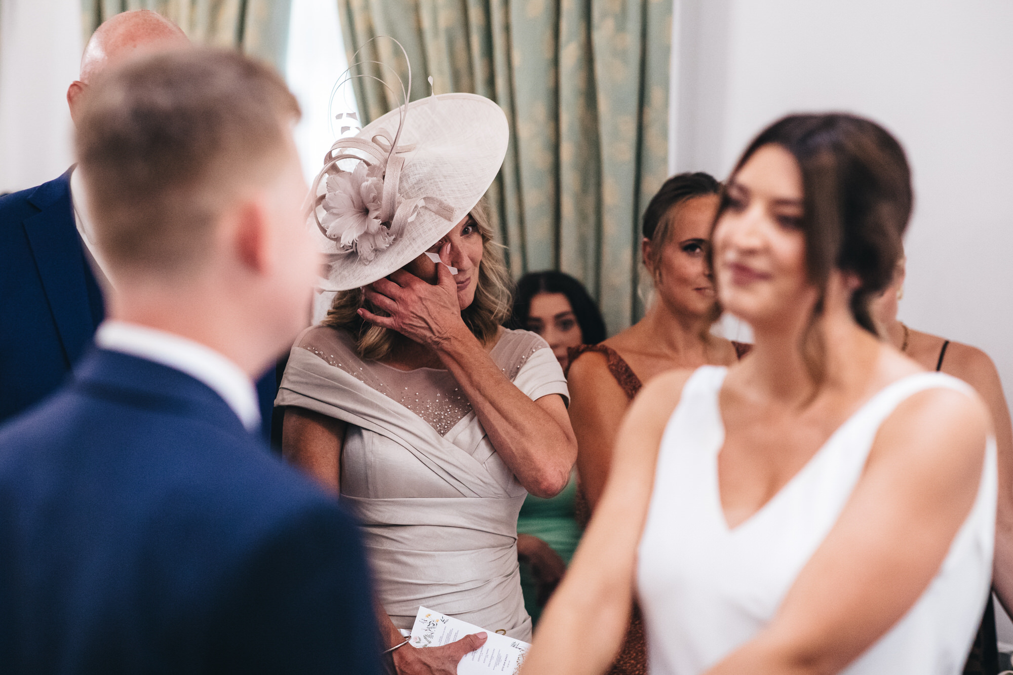 mother crying, wiping tears at ceremony with bride and groom