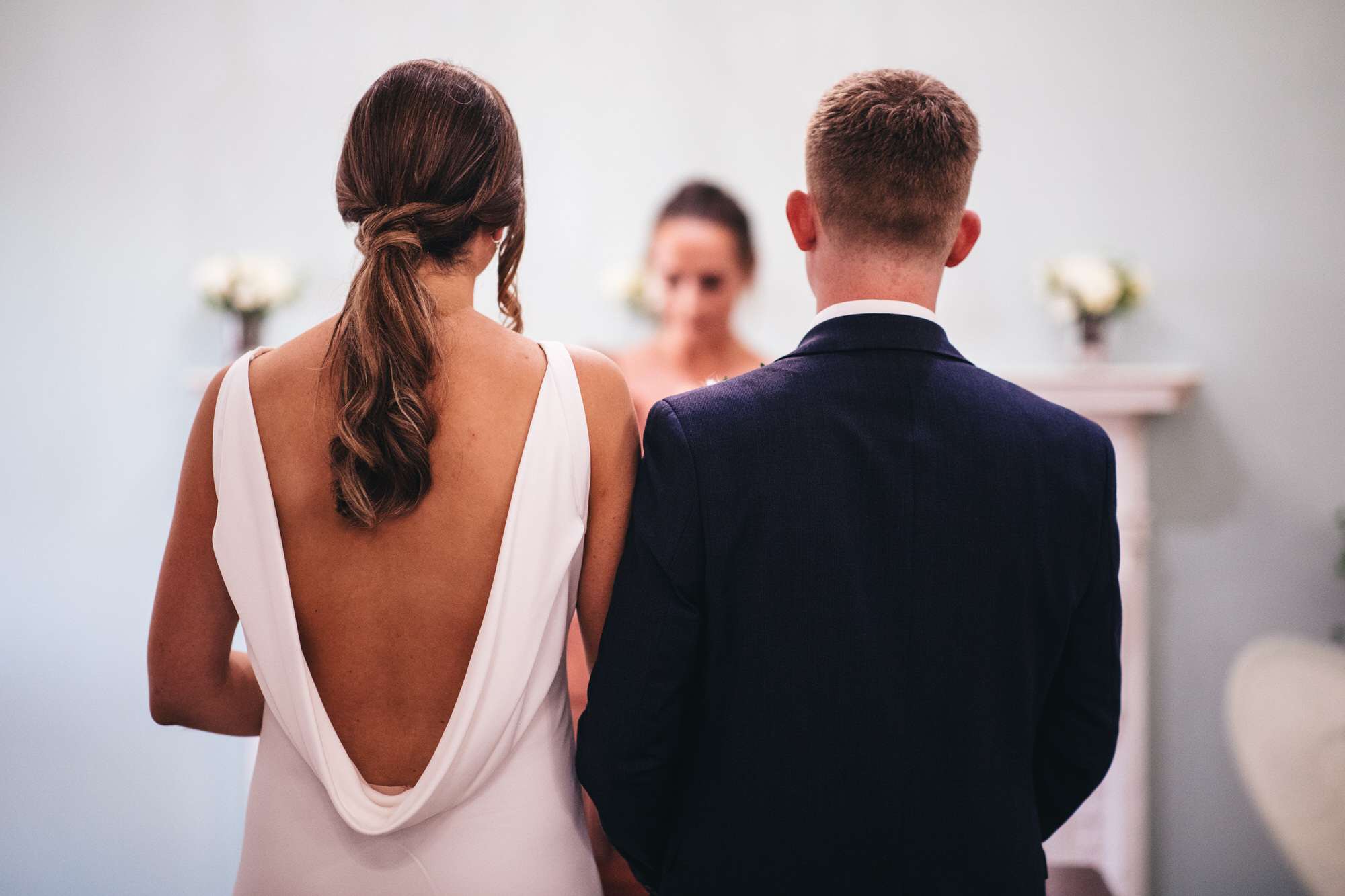 backless wedding dress, bride and groom at ceremony