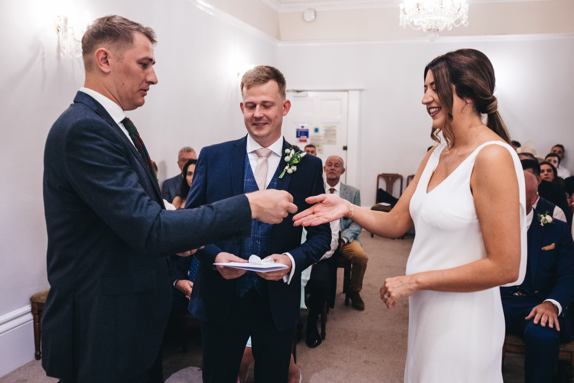 best man hands ring to bride at ceremony