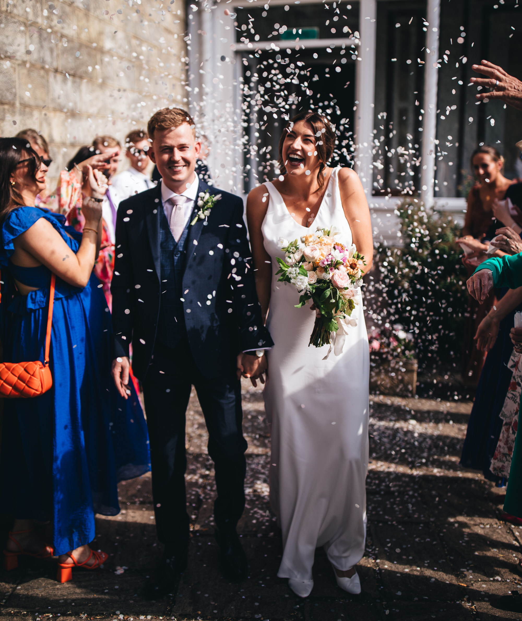 bride and groom walk through confetti