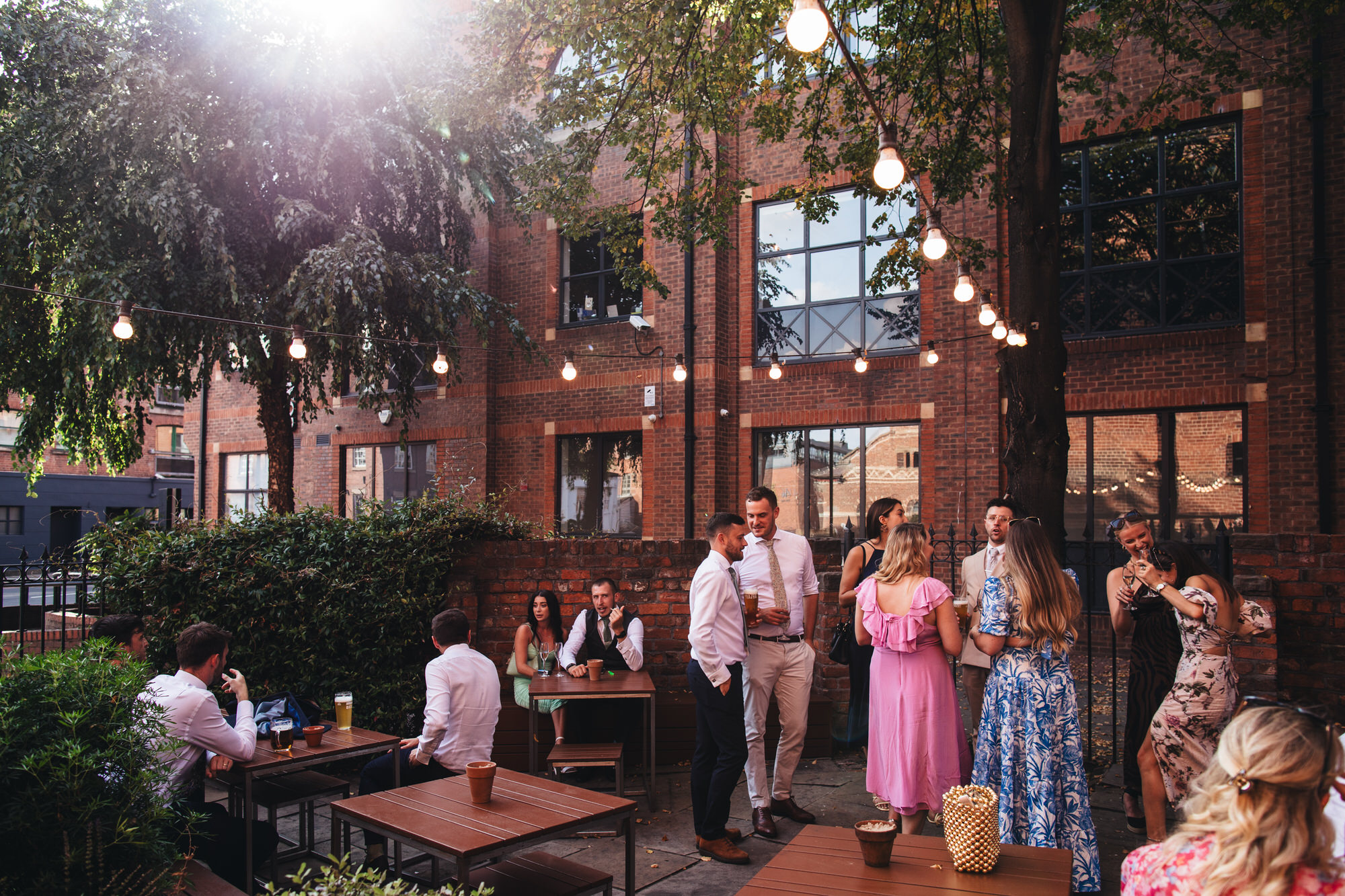 outdoor festoon lights outside shears yard with wedding guests drinking underneath
