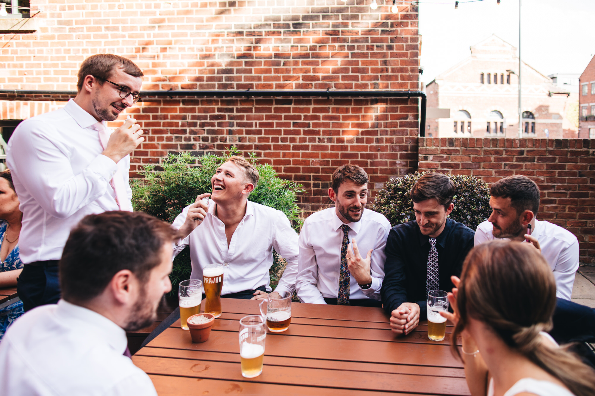 wedding guests, men sitting at table talking drinking pints of beer