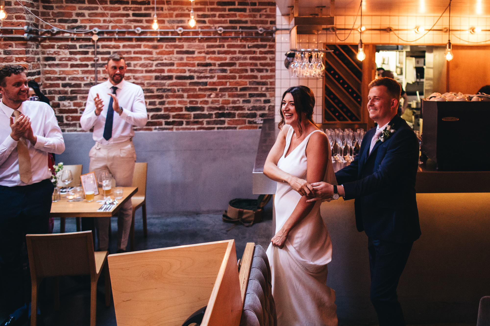 bride and groom enter room with guests clapping
