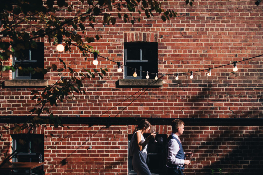 bride and groom walking underneath festoon lights