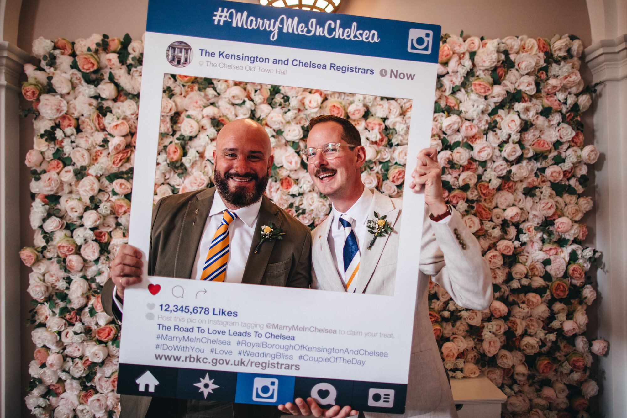 grooms in suits posing with instagram board from Kensington and Chelsea Registrars at Chelsea wedding