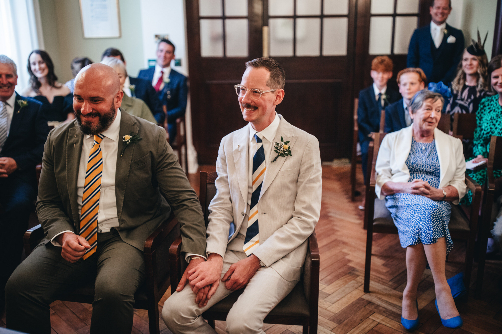 grooms hold hands together at Chelsea wedding