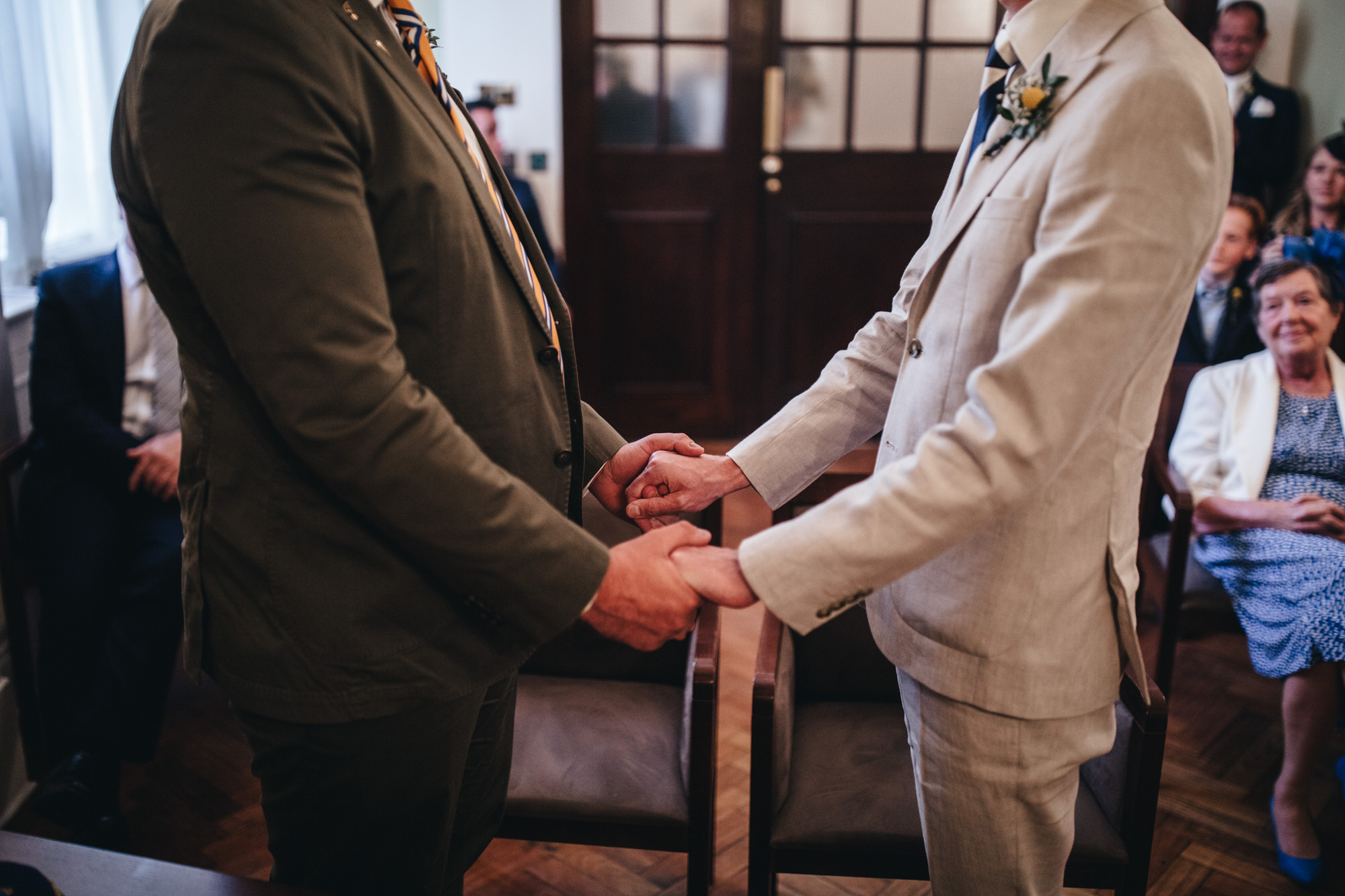 close grooms holding hands at Chelsea Old Town Hall wedding