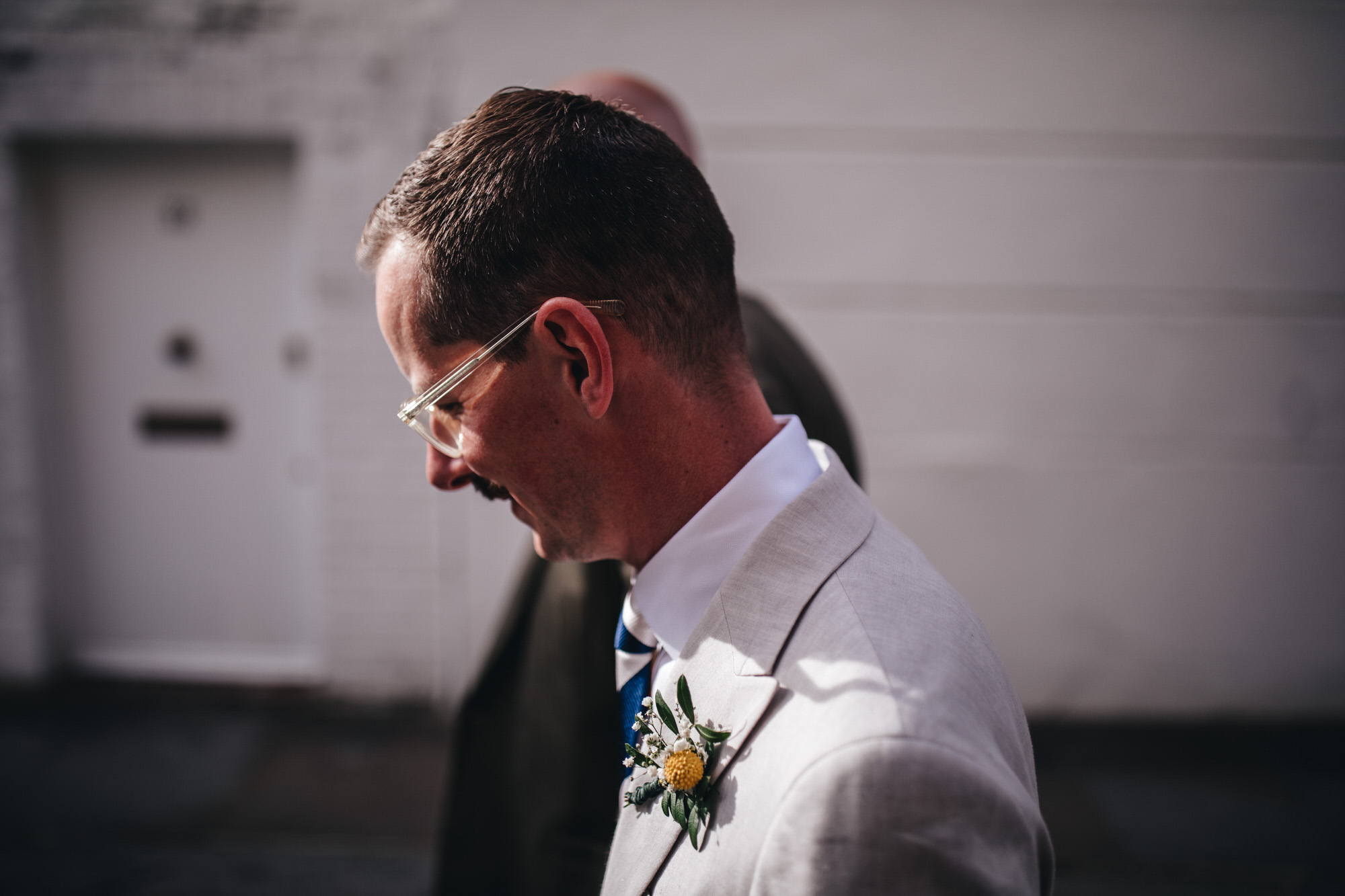 close groom wearing glasses and wedding buttonhole